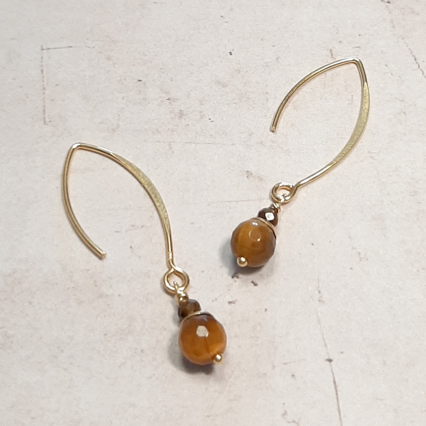 Boucles d’oreilles pendantes en argent 925 doré, ornées de pierres naturelles d’œil de tigre. Avec une longueur de 4,5 cm, elles présentent un design intemporel et raffiné.