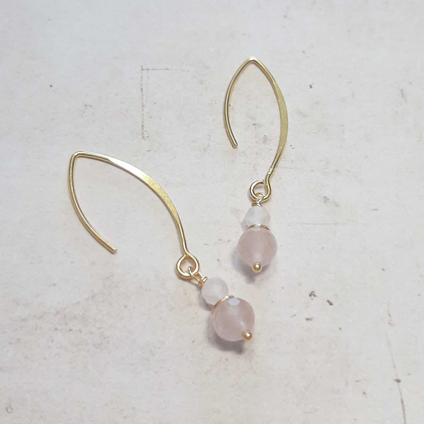 Boucles d’oreilles pendantes en argent 925 doré, d'une longueur de 4,5 cm. Chaque boucle est ornée de pierres naturelles de quartz rose de 4 mm et 6 mm de diamètre, apportant une touche élégante et subtile. Le design combine un métal doré avec des nuances douces de quartz rose pour un look sophistiqué et délicat.