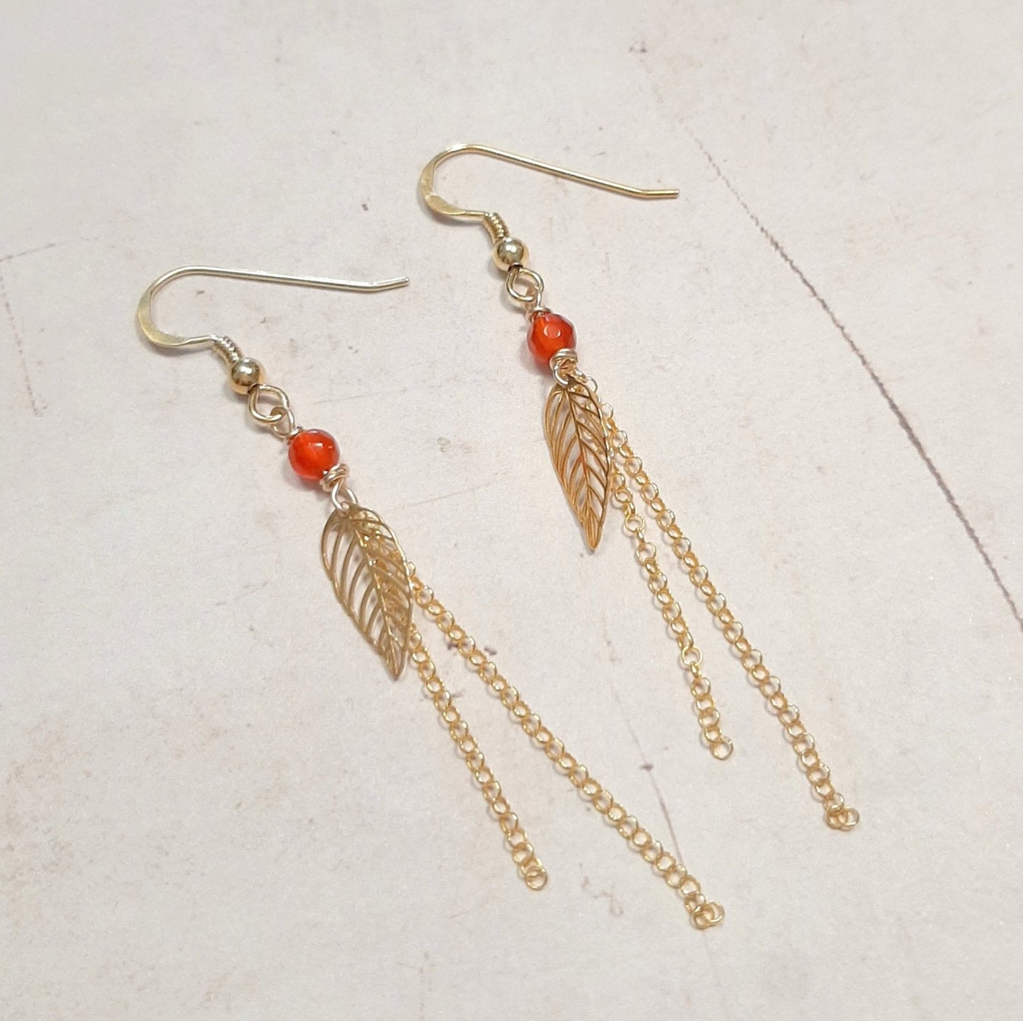 Boucles d’oreilles en argent 925 doré, composées de pierres naturelles de cornaline et ornées de chaînes délicates avec un pendentif en forme de feuille. La longueur est de 7 cm environ. ✨La cornaline, pierre énergétique et chaleureuse, ajoute une touche vibrante et élégante à votre look, parfaite pour apporter un éclat naturel et harmonieux.