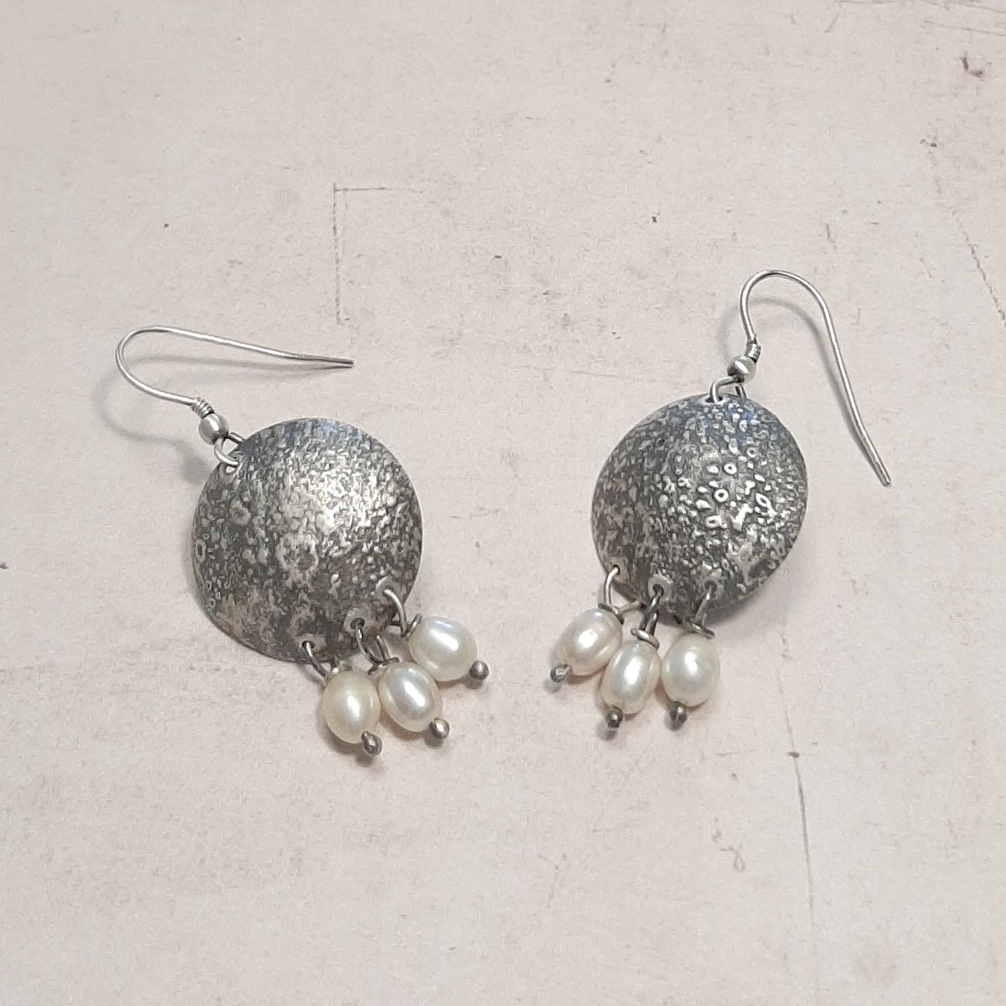 Boucles d’oreilles ethniques en argent massif texturé et perles de culture. Un bijou artisanal unique et raffiné.