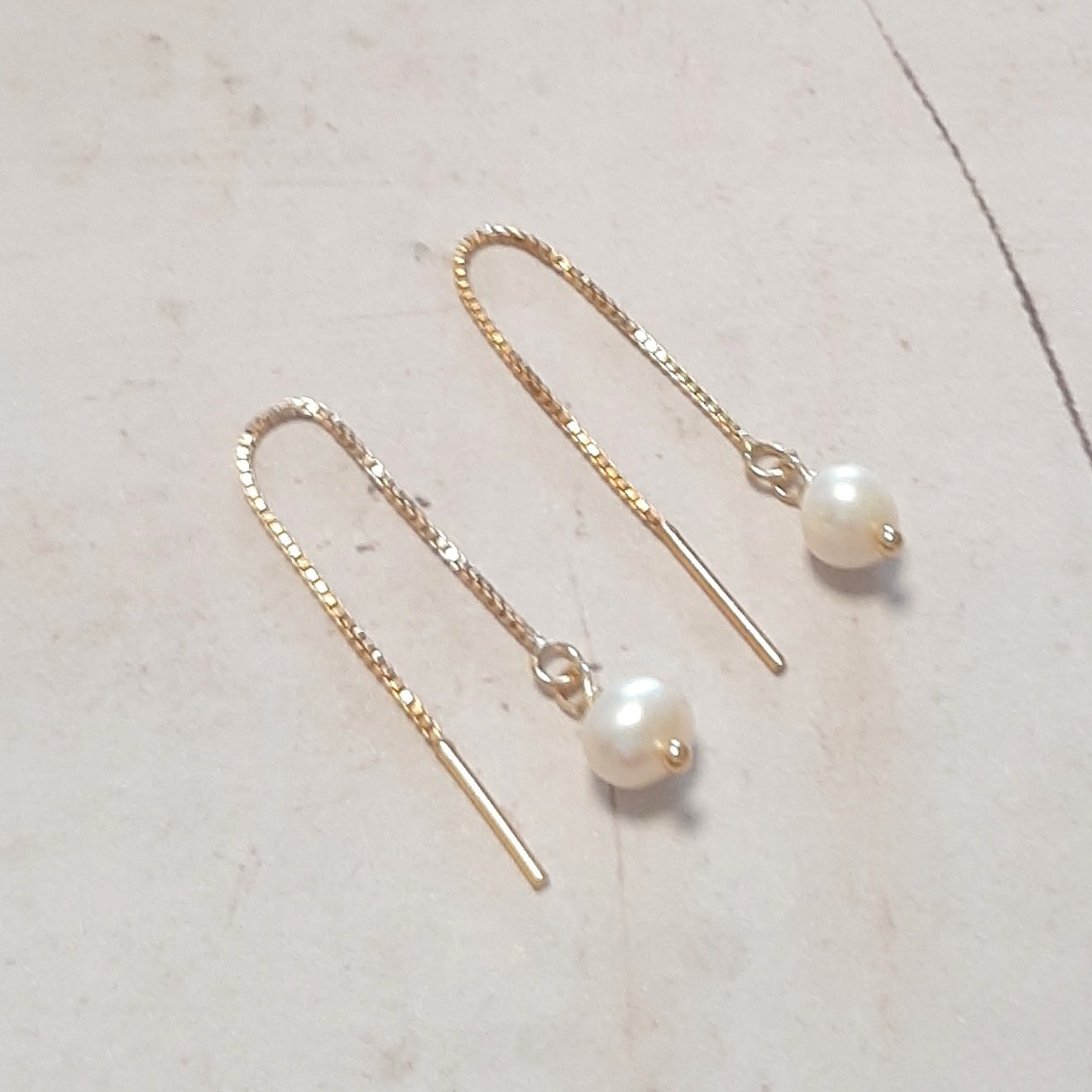 Boucles d’oreilles Ilhéus – Chaînes ajustables en argent doré et perles de culture
Laissez-vous séduire par la délicatesse des boucles Ilhéus, où la lumière caresse chaque perle avec douceur. En argent 925 doré à l’or fin 24 carats, ces boucles d’oreilles jouent avec la simplicité et l’élégance intemporelle.
Grâce à leur chaîne ajustable, vous pouvez les porter de différentes manières : en laissant la chaîne onduler librement ou en la glissant à travers plusieurs perçages pour un effet graphique et raffiné
