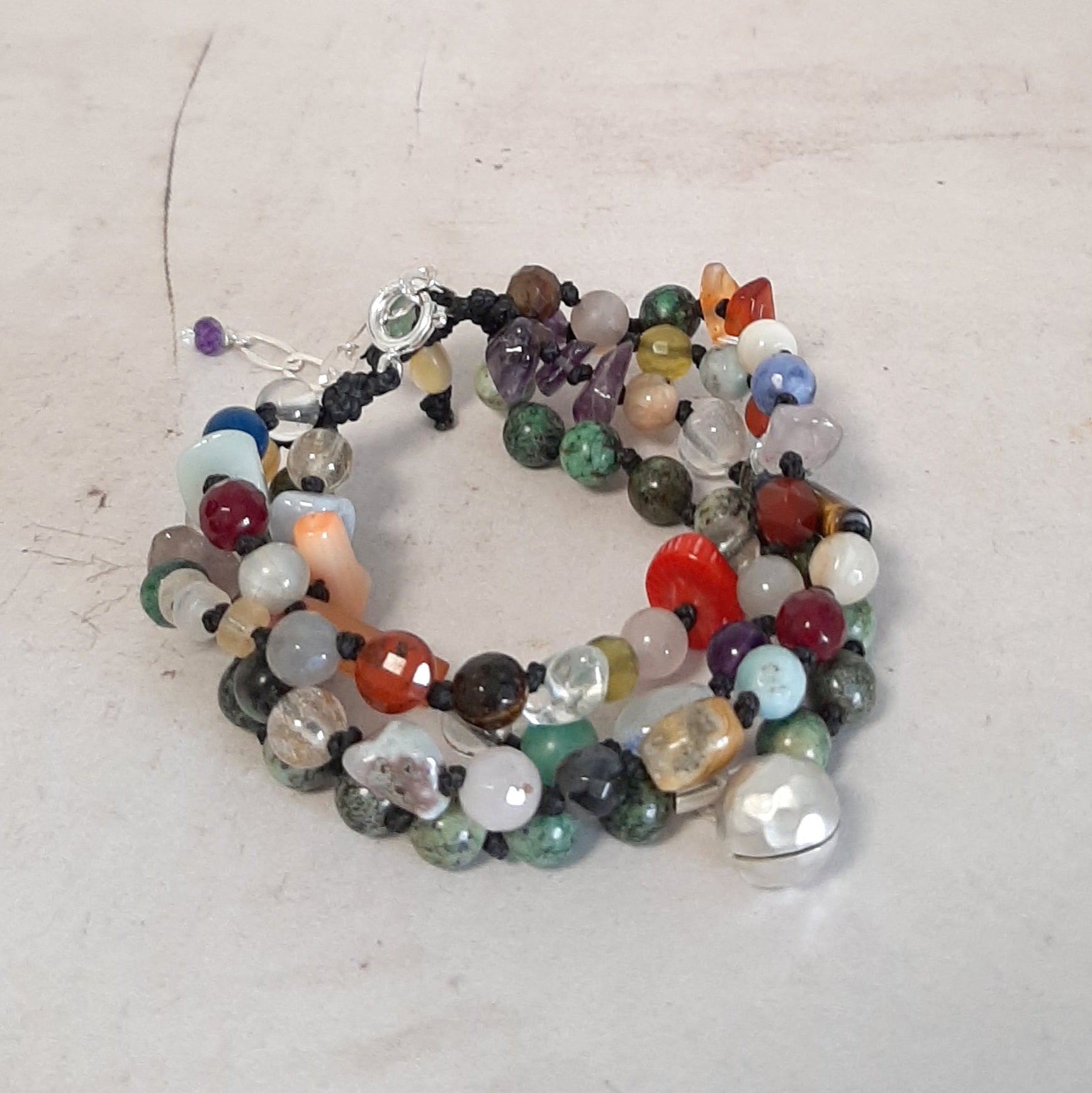 Bracelet brésilien réglable avec pierres naturelles multicolores et grelot appeleur d’anges. Un bijou bohème et spirituel, fait main.