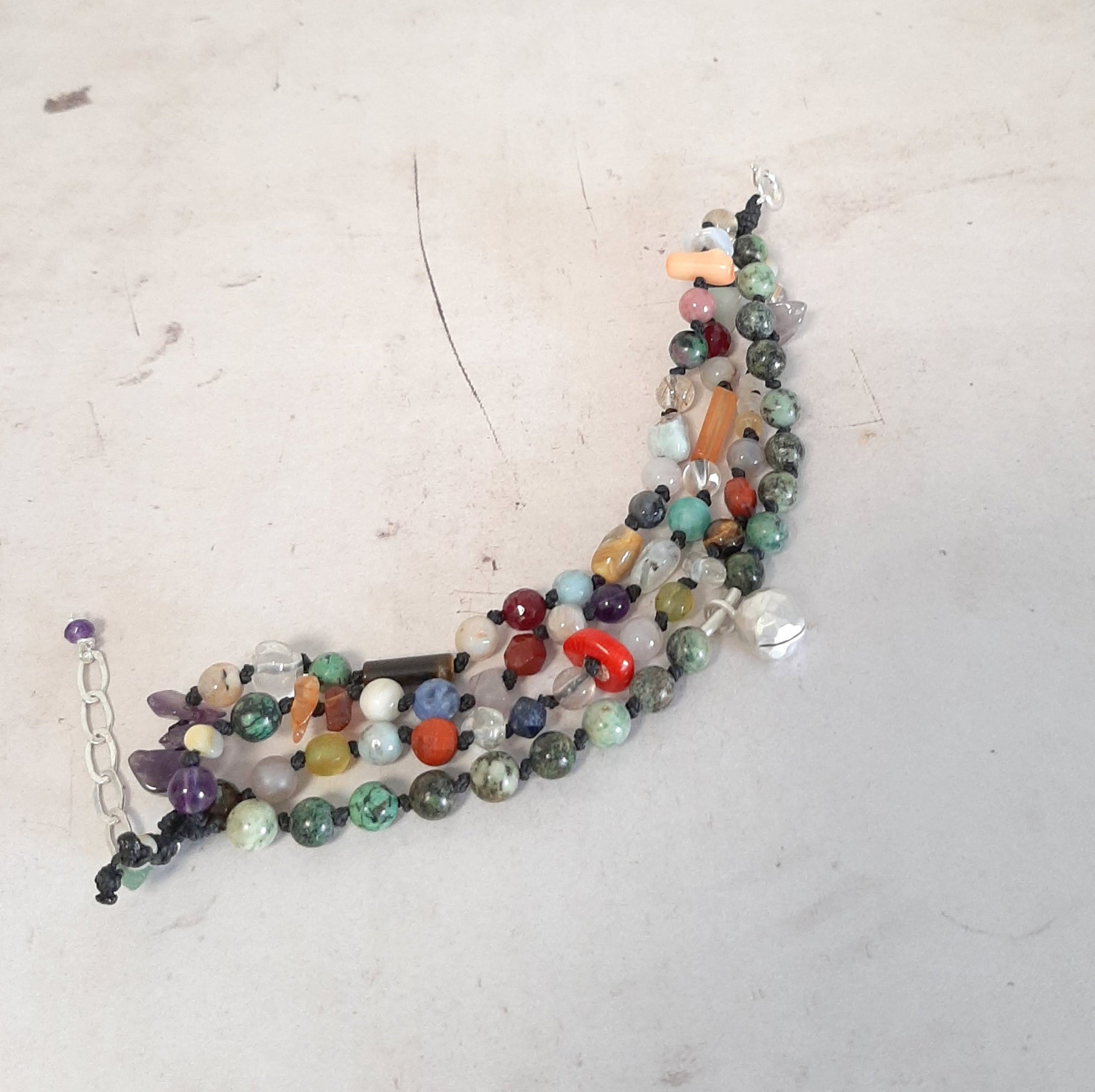 Bijou artisanal coloré, ce bracelet en pierres naturelles  porte un grelot appeleur d’anges pour attirer douceur et protection.