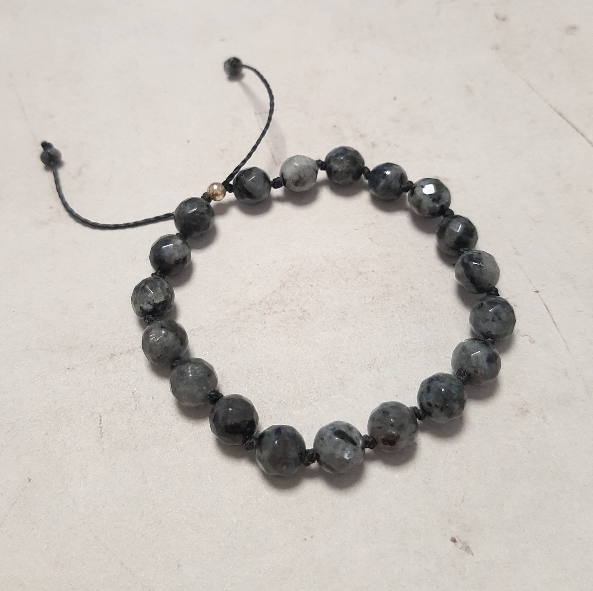 Un bracelet épuré en argent 925 et larvikite, aussi appelée labradorite noire. Réglable grâce à son cordon coulissant, il s’adapte à tous les poignets. Un bijou mixte aux énergies d’ancrage.