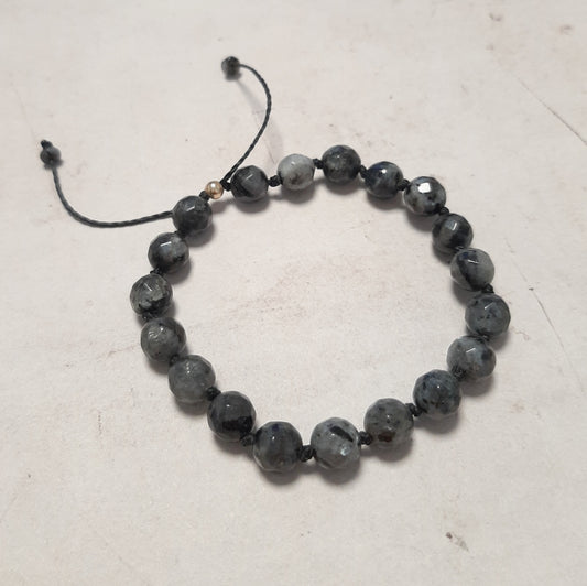 Un bracelet épuré en argent 925 et larvikite, aussi appelée labradorite noire. Réglable grâce à son cordon coulissant, il s’adapte à tous les poignets. Un bijou mixte aux énergies d’ancrage.