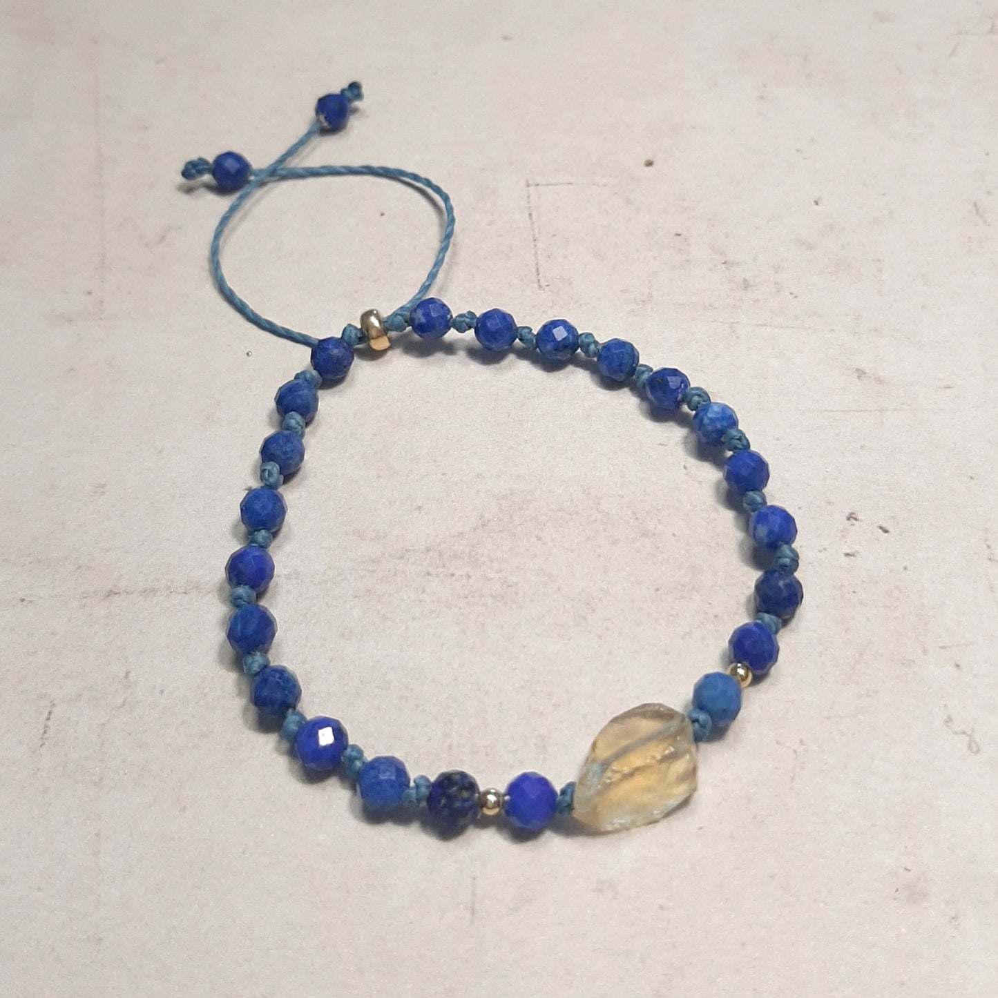 Bracelet ajustable en pierres naturelles – Lapis-lazuli, citrine et argent doré
Laissez-vous séduire par l’alliance du bleu profond du lapis-lazuli et de l’éclat solaire de la citrine. Ce bracelet réglable, orné d’apprêts en argent 925 doré, s’adapte à toutes les tailles de poignet. Chaque pierre étant naturelle, chaque bijou est une création unique.