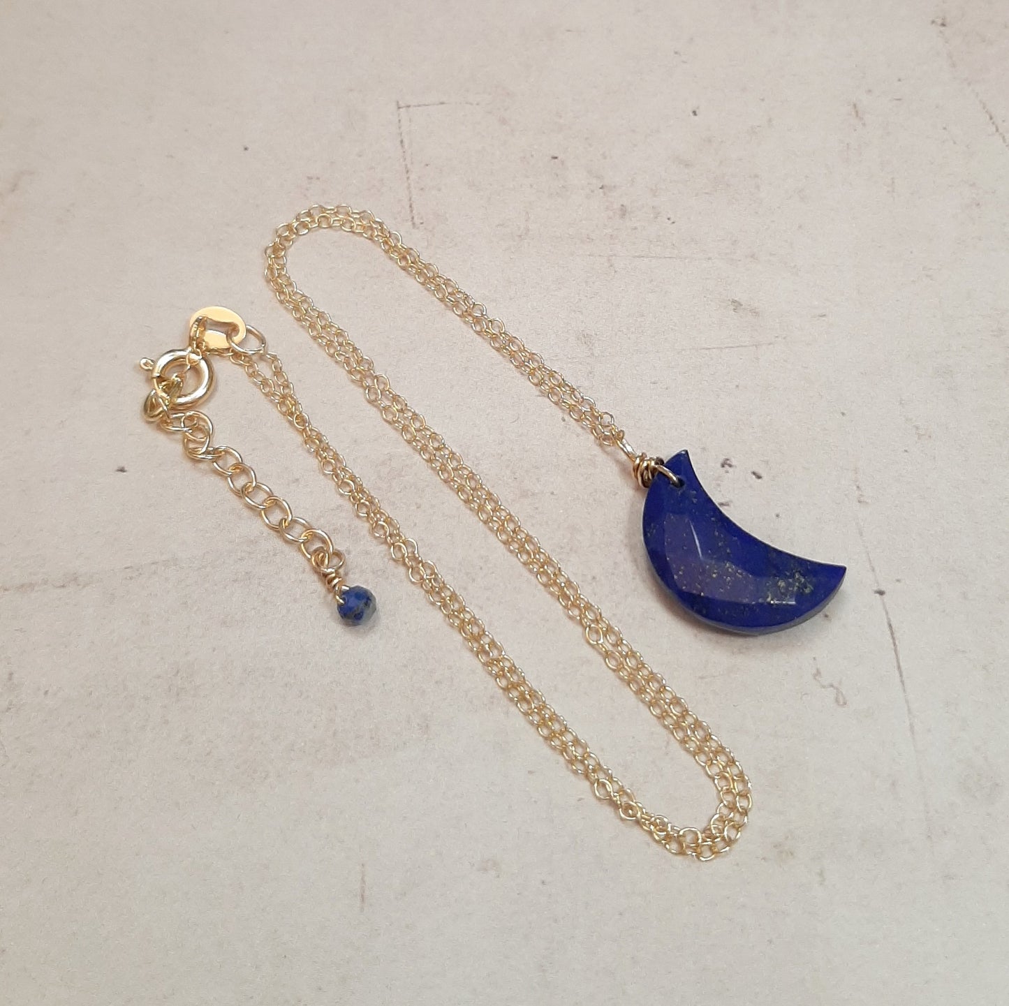 Collier en argent sterling doré, orné d'un pendentif en forme de croissant de lune en lapis lazuli. La lapis lazuli, avec ses teintes bleu profond, évoque à la fois la sagesse et la protection spirituelle. Ce collier est non seulement un accessoire élégant, mais aussi un talisman puissant qui encourage la confiance en soi et l'alignement spirituel.