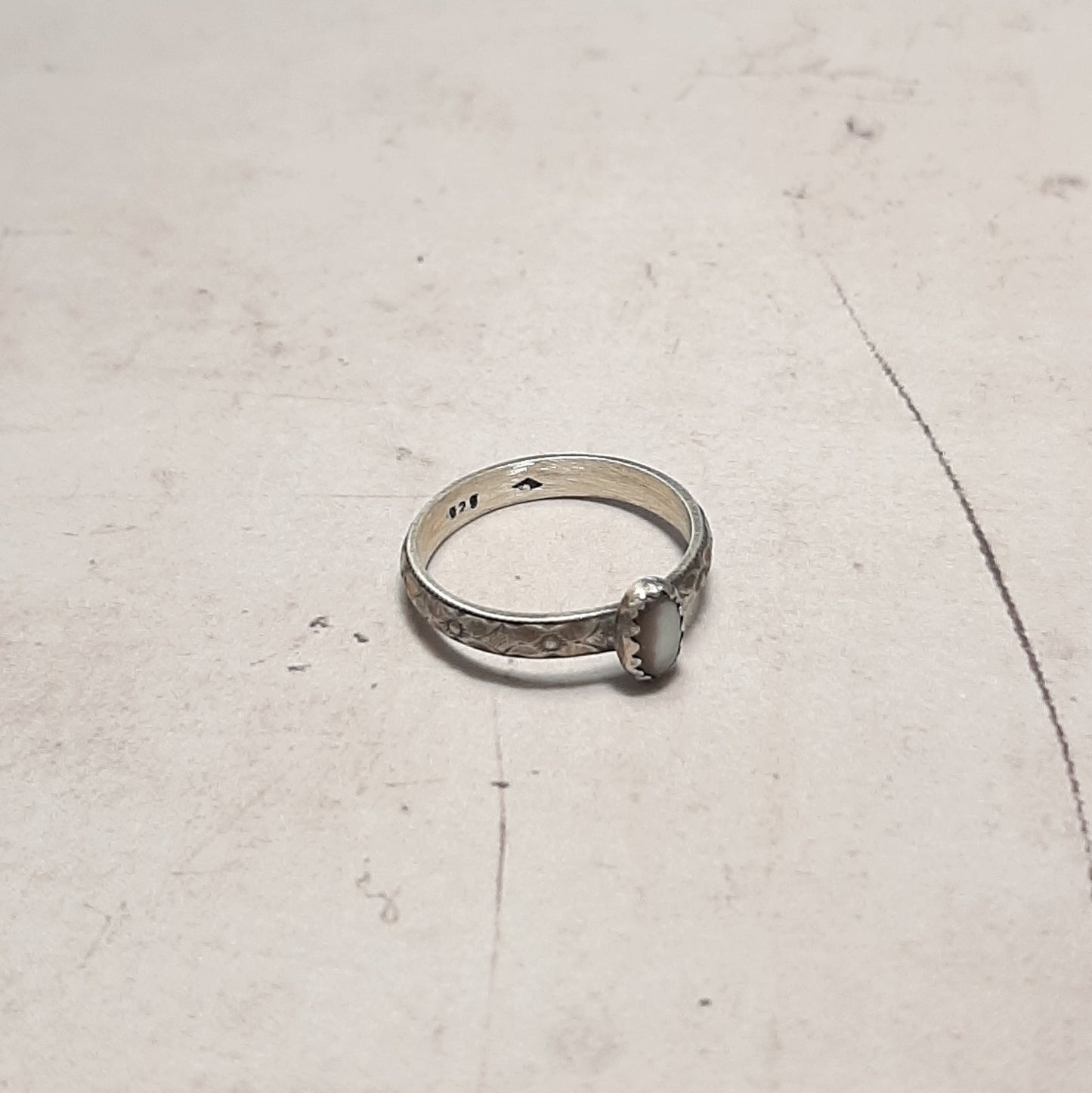 Plongez dans l'univers de l'artisanat avec cette bague ethnique en argent massif, ornée d'une nacre perlière aux reflets irisés. Inspirée par la nature, ses motifs floraux délicats évoquent la beauté des fleurs sauvages. Une pièce intemporelle pour celles qui aiment sublimer leur style avec élégance et simplicité.