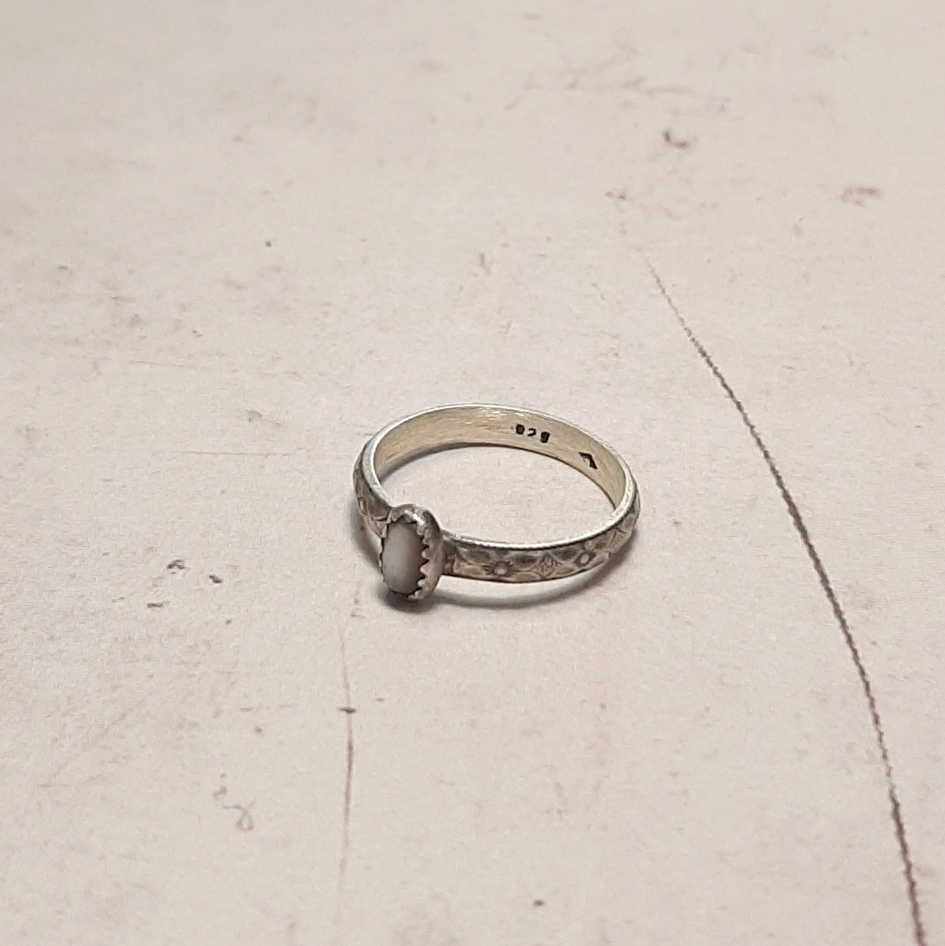 Cette bague en argent massif patiné est l'expression même du romantisme. La nacre perlière, subtile et lumineuse, est mise en valeur par des motifs floraux finement gravés. Un bijou raffiné qui apporte une note de douceur à vos tenues, parfait pour les amoureuses de la nature et des bijoux faits à la main.