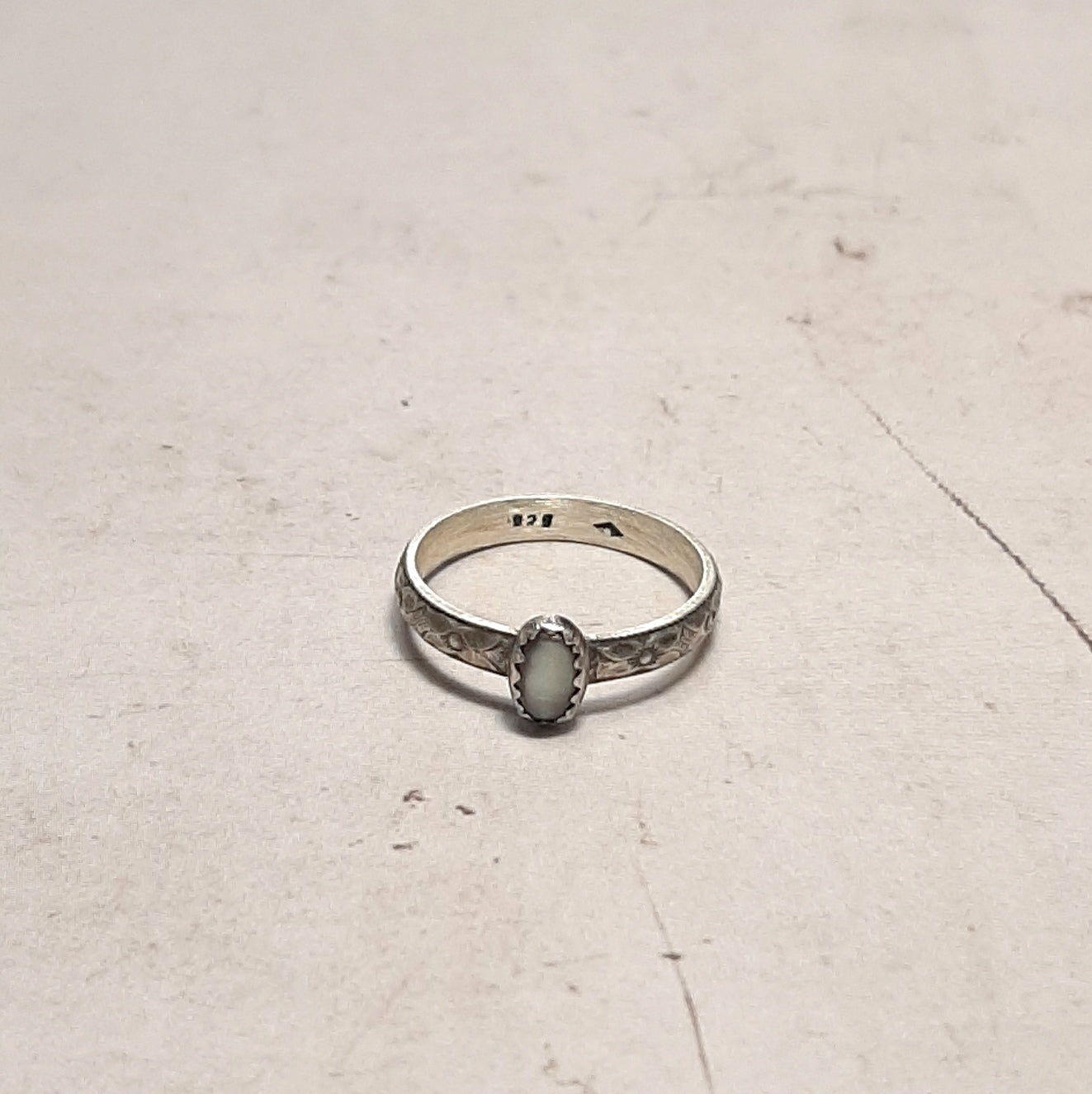 Façonnée en argent massif patiné, cette bague incarne l'art de l'artisanat. La nacre perlière naturelle, capturant la lumière avec ses reflets irisés, confère à cette pièce une élégance singulière. Les motifs floraux sculptés ajoutent une dimension bohème-chic, idéale pour les esprits libres et les amateurs de bijoux authentiques.