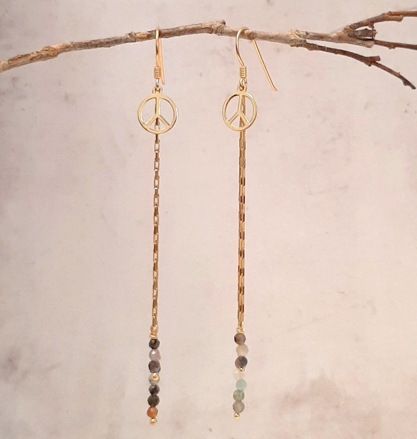 Ces boucles d'oreilles longues sont fabriquées à la main avec de l'argent 925 doré et des pierres naturelles de tourmaline. Elles sont ornées d'une médaille de la paix. Ce bijou bohème est unique et élégant. Il est parfait pour offrir ou pour se faire plaisir.