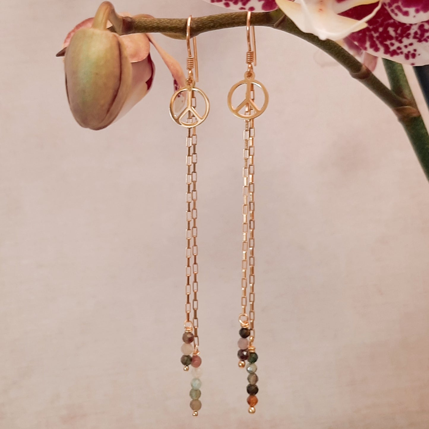 Ces boucles d'oreilles longues sont fabriquées à la main avec de l'argent 925 doré et des pierres naturelles de tourmaline. Elles sont ornées d'une médaille de la paix. Ce bijou bohème est unique et élégant. Il est parfait pour offrir ou pour se faire plaisir.