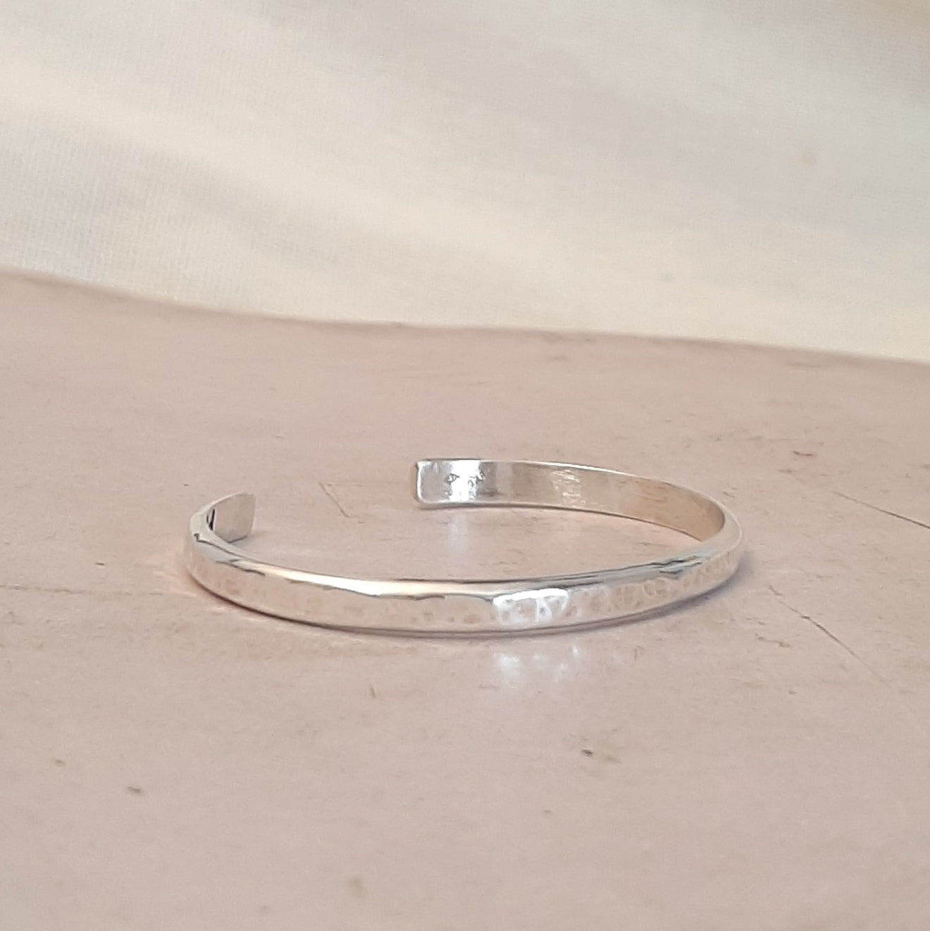 Bracelet jonc ouvert en argent massif martelé, avec un design épuré. Taille unique et réglable, s'adaptant facilement au poignet pour un confort optimal. Un bijou intemporel et élégant. Diamètre intérieur de 60 mm, épaisseur de 5 x 2,5 mm.