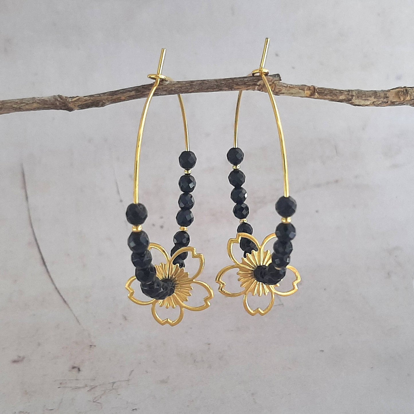 Sublimez votre look avec ces élégantes créoles dorées en argent 925, ornées de pierres d'onyx naturelles et d'une délicate fleur estampée. Le contraste entre l'argent et l'onyx apporte une touche de sophistication à ces boucles d'oreilles, parfaites pour toutes les occasions. La fleur estampée ajoute une note bohème et romantique. Confectionnées avec soin, ces créoles sont un véritable écrin pour vos oreilles.