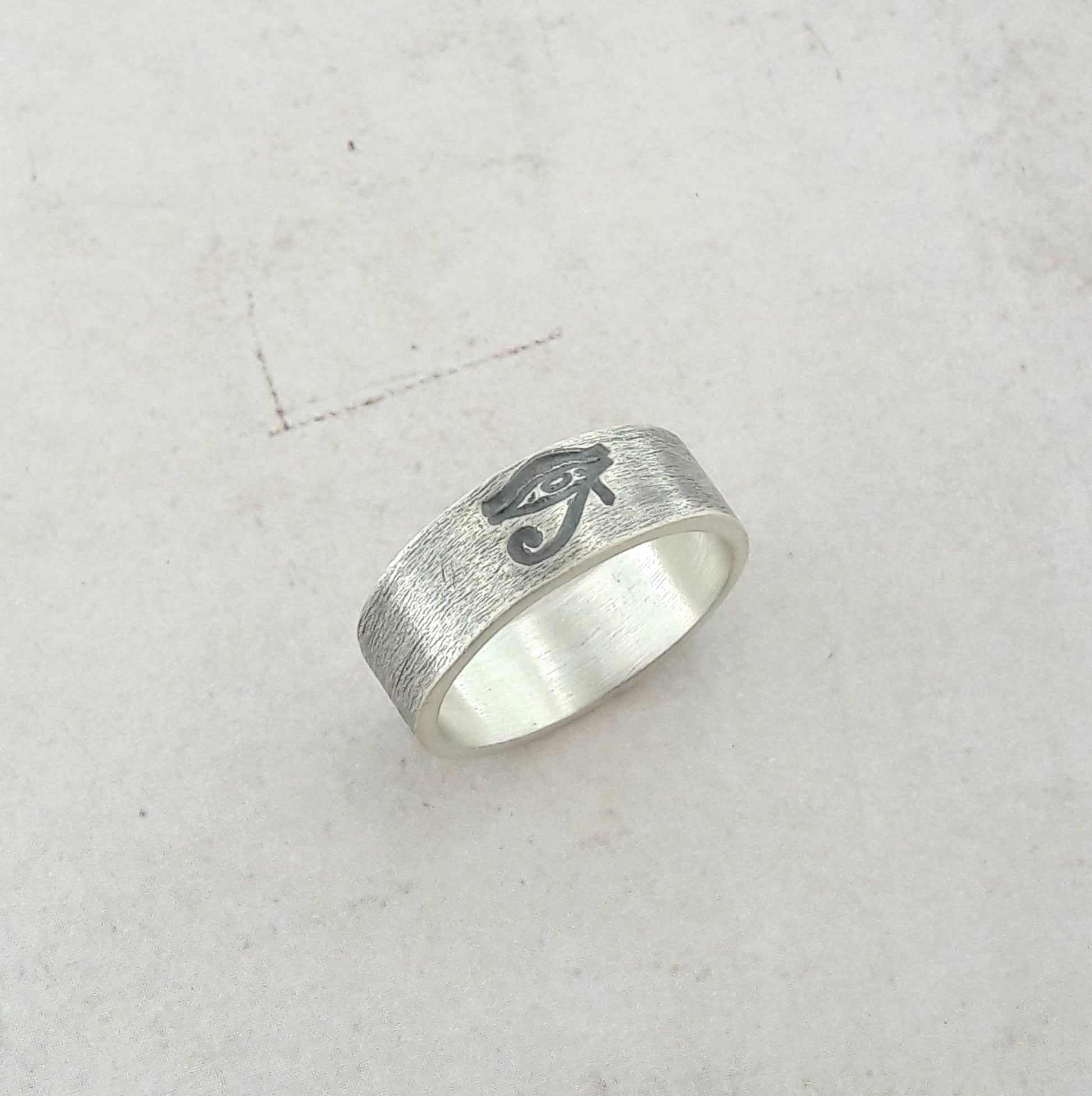 La bague "Œil d'Horus" en argent massif patiné, avec une largeur d'environ 6 mm, se distingue par son design symbolique et intemporel. Unisexe, elle convient aussi bien aux hommes qu'aux femmes. L’Œil d’Horus, également appelé oudjat, est un symbole ancien de protection et de clairvoyance, souvent porté comme un porte-bonheur. Fabriquée sur commande, elle est expédiée sous un délai de 5 jours, garantissant une pièce unique et personnelle. Idéale pour enrichir un style avec une touche d’exotisme et d’histoir