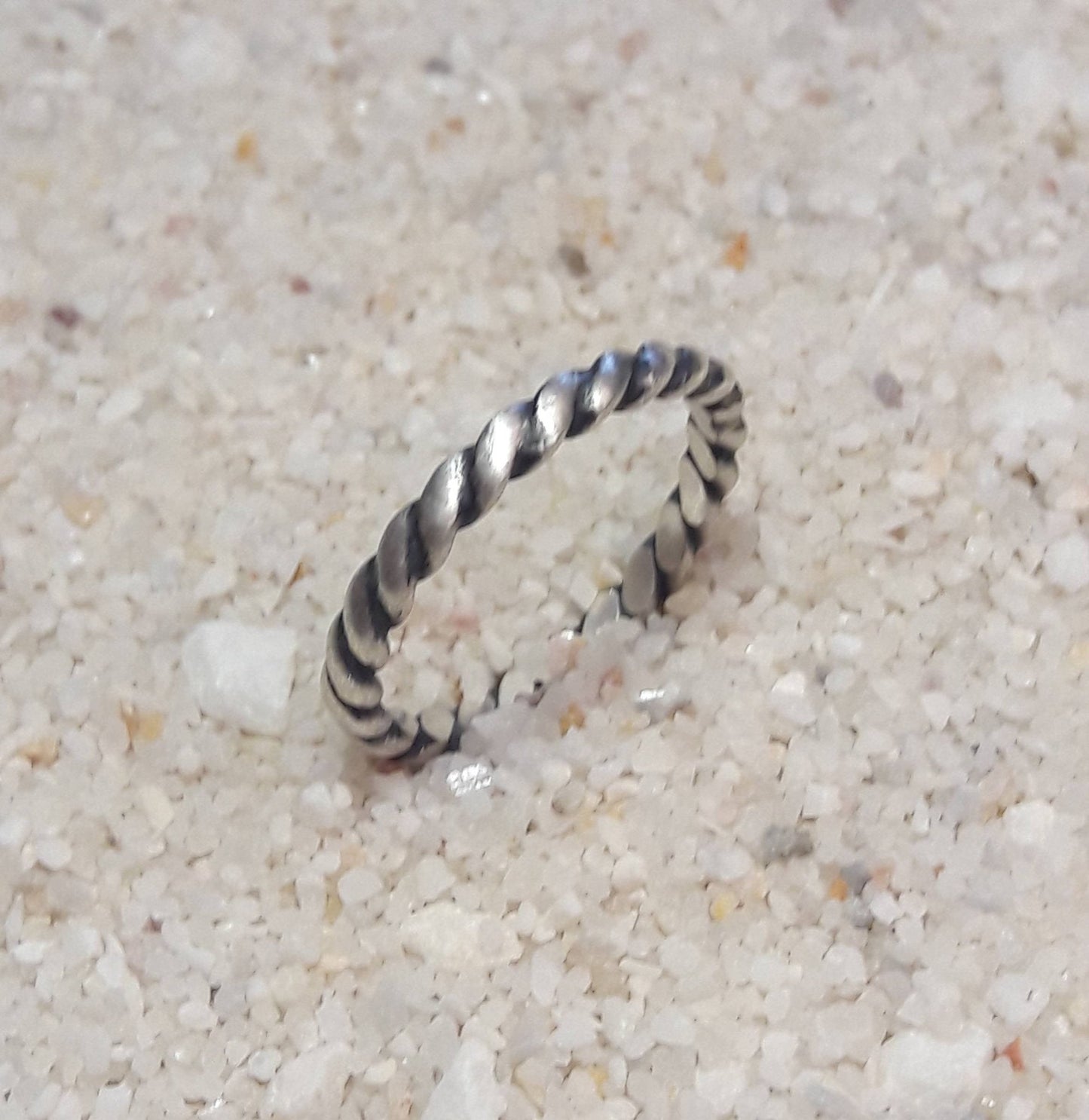 Bague torsadée fabriquée en argent massif patiné, alliant élégance et rusticité. Son design artisanal offre une touche d'originalité tout en restant intemporel, convenant aussi bien aux hommes qu'aux femmes. Avec une largeur d’environ 2,6 mm, ce bijou distinctif reflète une esthétique authentique, parfaite pour symboliser un engagement, une amitié, ou pour offrir à quelqu'un qui apprécie les pièces uniques et pleines de caractère.