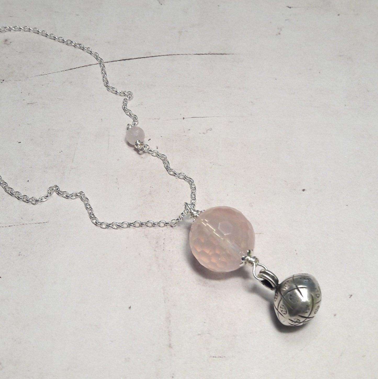 Bijoux de grossesse, sautoir bola argent 925 et pierres naturelles de quartz rose Ce sautoir est confectionné avec une chaîne en argent 925/1000, accompagnée d'un pendentif en quartz rose facetté, une pierre naturelle réputée pour ses propriétés apaisantes. Une petite cloche en argent 925/1000 ajoute une touche délicate à cet ensemble élégant et plein de sens. bijoux de grossesse, sautoir bola argent 925, cadeau femme, femme enceinte, quartz rose, bijoux pour femmes enceintes.