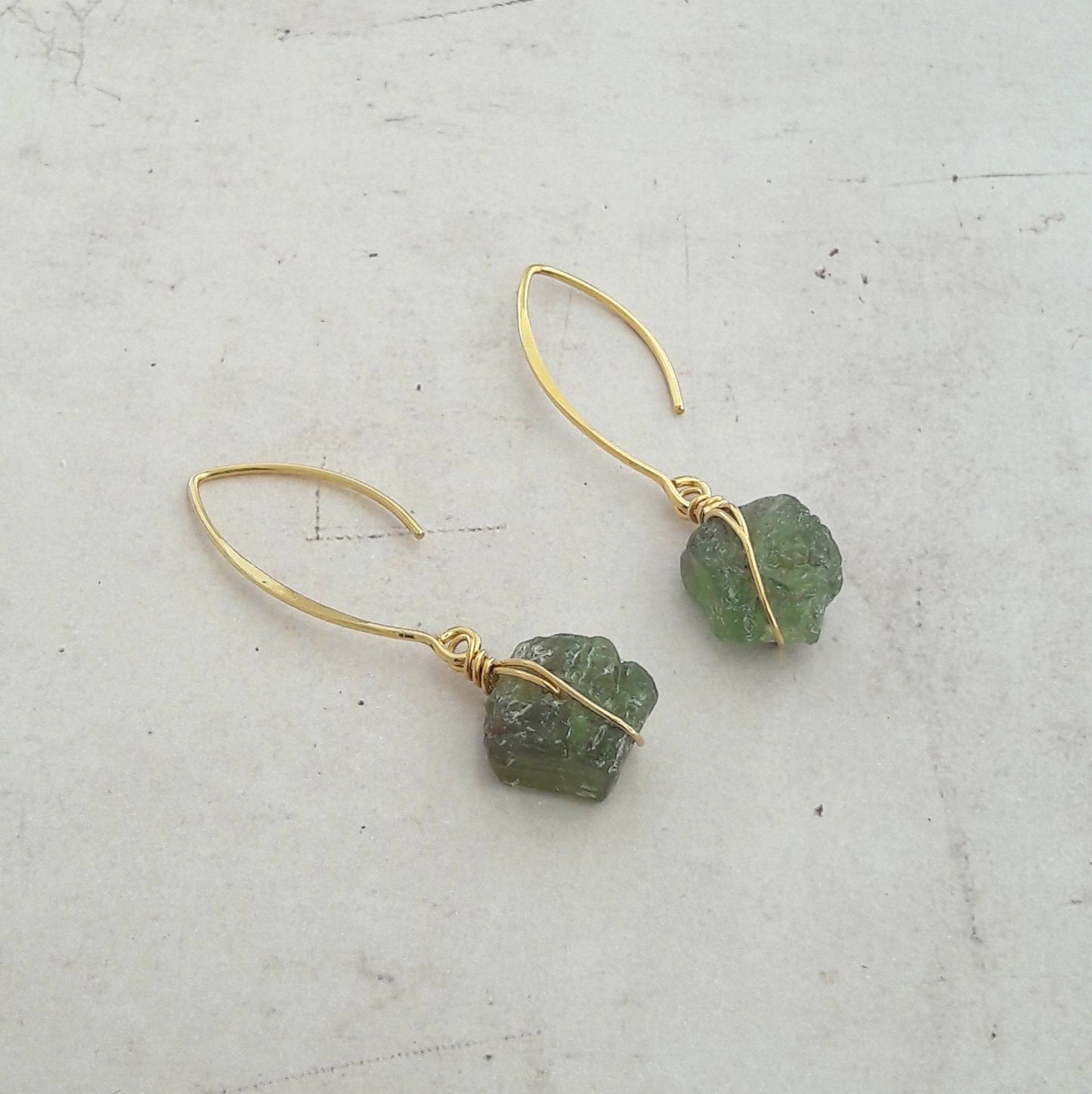 Boucles d'oreilles en argent 925 doré à l'or fin, ornées de pierres naturelles brutes de grenat vert. Les pierres, naturelles, peuvent présenter des variations légères de couleurs et de formes. Longueur : 5.5 cm environ ✨Le grenat vert, pierre énergisante, est réputé pour apporter détermination, dynamisme et courage à son porteur.