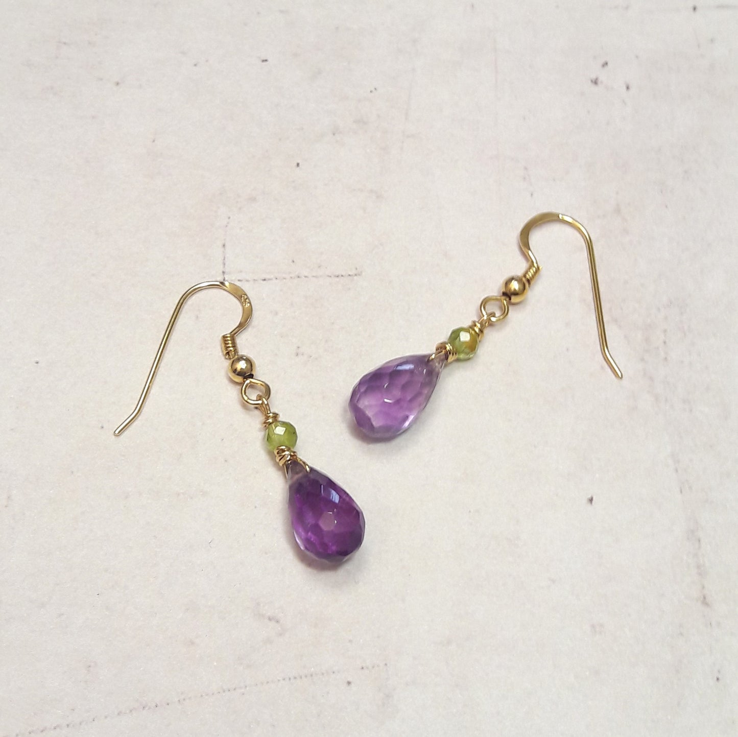 Ces boucles d’oreilles en argent massif associent la douceur de l’améthyste et l’éclat du péridot. Un duo de pierres naturelles pour un bijou raffiné, lumineux et plein d’énergie.