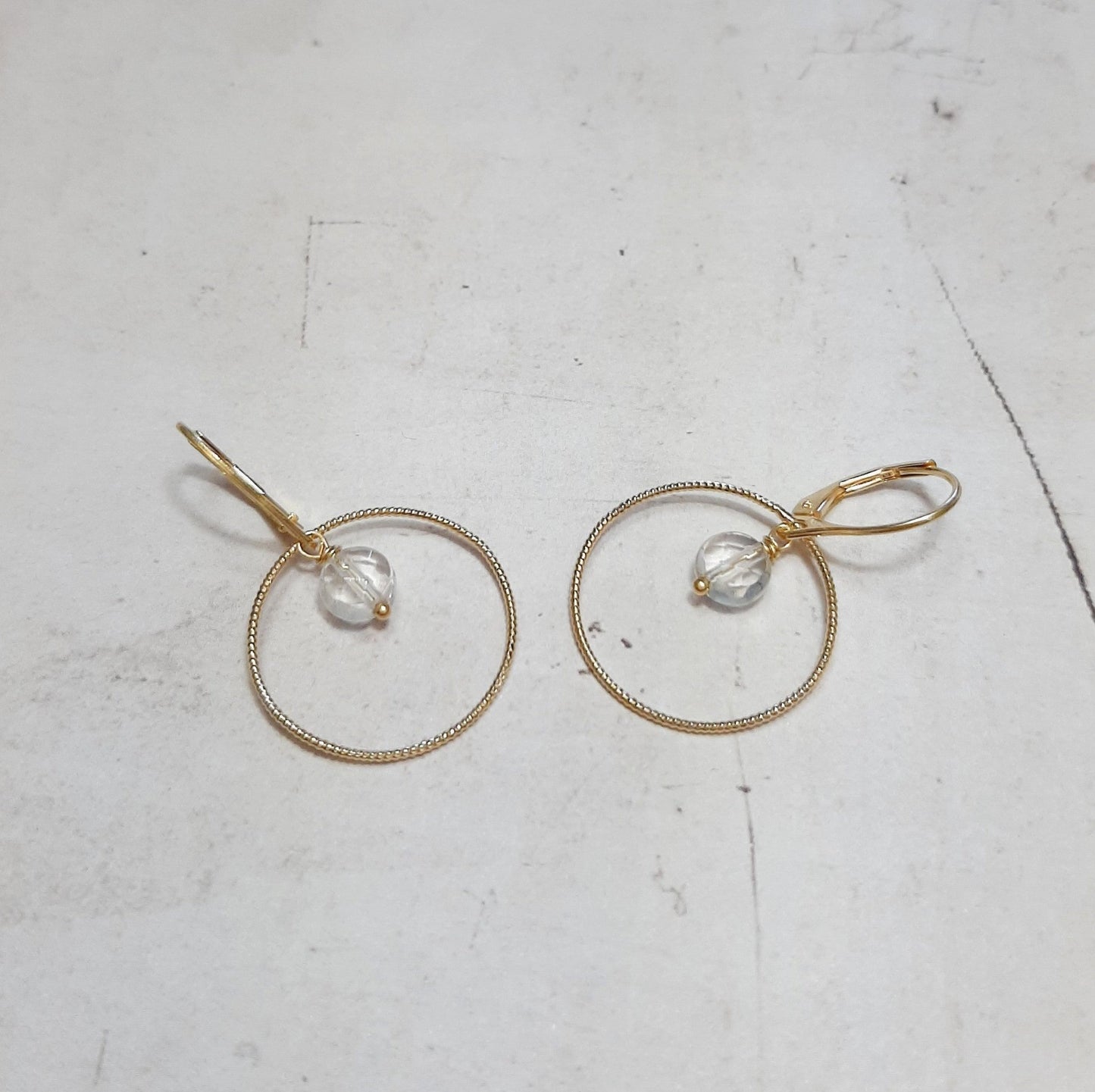 Boucles d'oreilles type dormeuses avec anneaux ciselés ornées de pierres naturelles de cristal de roche facetté. Longueur : 3.5 cm environ