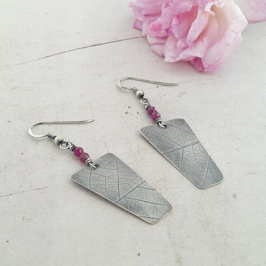 Boucles d'oreilles ethniques en argent massif patiné, ornées de rubis. Chaque bijou, façonné à la main, présente des petites différences, rendant chaque pièce unique. La longueur est d'environ 5,7 cm, offrant une présence élégante et distinctive. Le rubis redonne la joie de vivre, développe la confiance en soi et la persévérance, et dans la tradition indienne, il favorise la réussite matérielle.