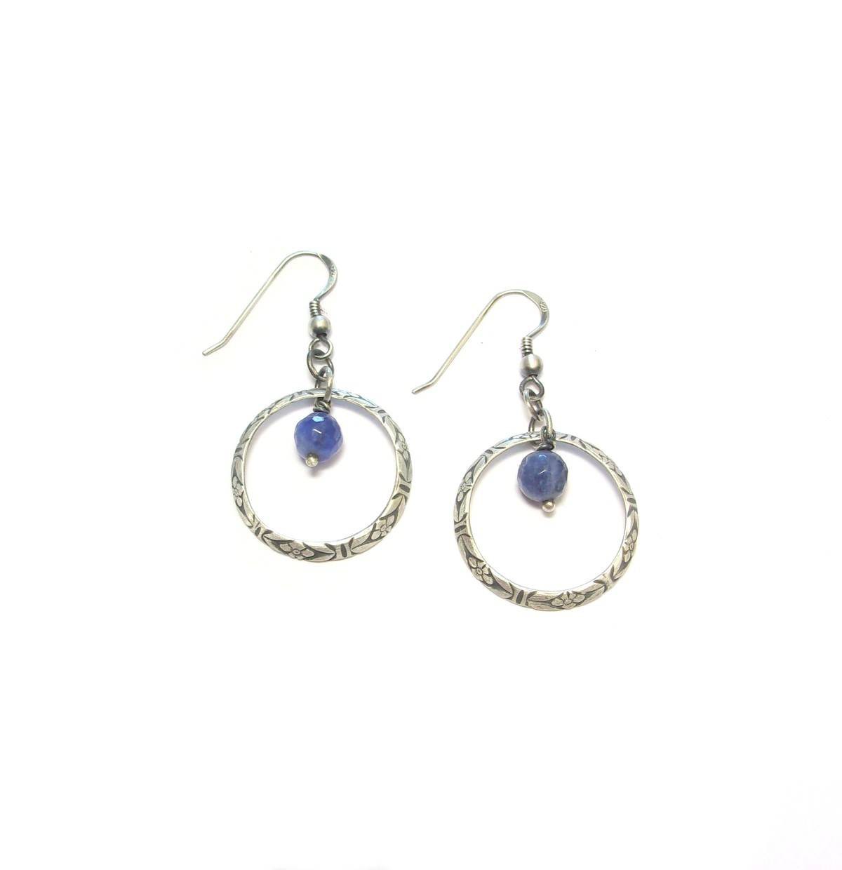 Découvrez les boucles d'oreilles Terena, une création unique en argent massif patiné et sodalite. Inspirées de l'esthétique ethnique, elles associent la brillance de l'argent 925 à la profondeur bleutée de la sodalite, pierre connue pour ses vertus apaisantes. Parfaites pour les amateurs de bijoux artisanaux et de lithothérapie, ces boucles d'oreilles apporteront une touche d'originalité et de sérénité à votre quotidien.