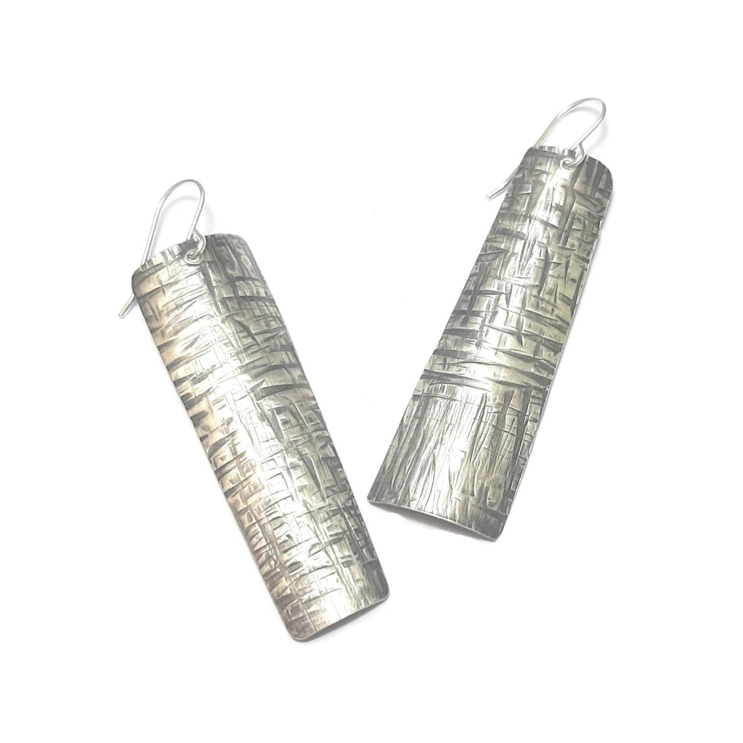 Boucles d'oreilles ethniques en argent massif martelé, légèrement asymétriques. Les reliefs, révélés par la patine, évoquent le tronc du "tucum", palmier tropical.