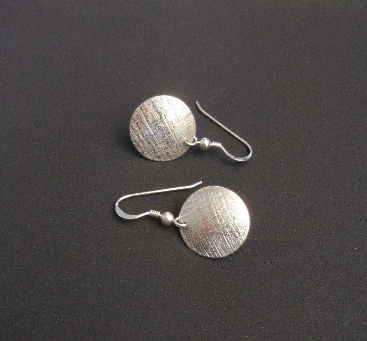 Boucles d'oreilles rondes en argent massif, avec un design délicatement ciselé apportant une touche d'élégance subtile. Leur légèreté et discrétion les rendent idéales pour une utilisation quotidienne, ajoutant une note de style raffinée à toutes les tenues.