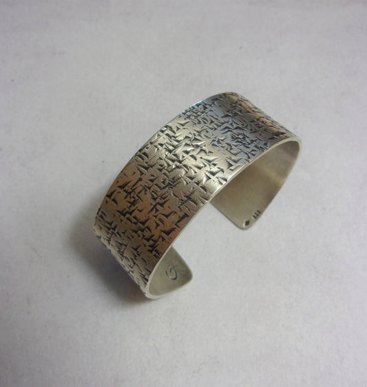 Bracelet ethnique en argent massif martelé, façonné à partir d'une plaque d'argent et patiné à la main. Cette manchette rigide dégage une élégance intemporelle.