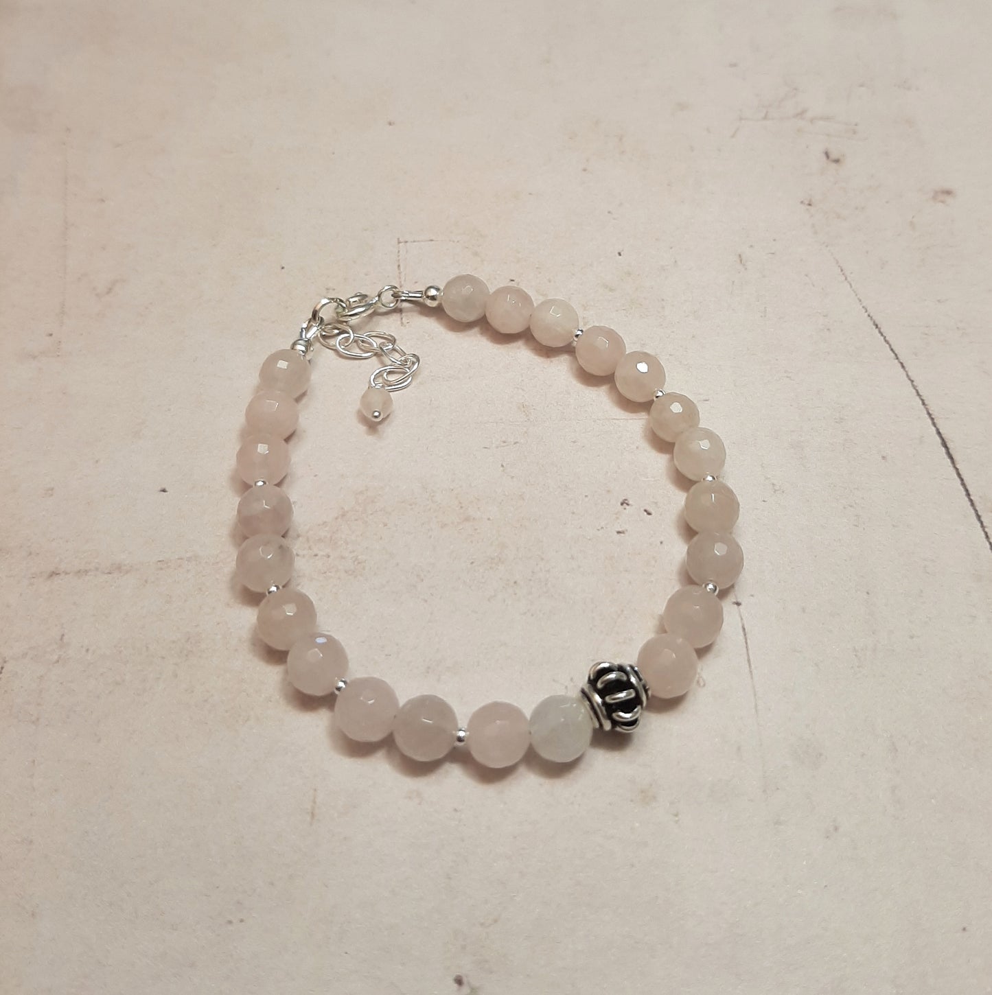 Ce bracelet délicat marie la tendresse du quartz rose, pierre de l'amour et de la paix intérieure, avec la pureté de l'argent 925. Chaque perle de quartz rose de 6 mm est soigneusement sélectionnée et assemblée à la main en France, créant un bijou qui symbolise la douceur et l'élégance. Avec une longueur de 17 cm et une chaînette ajustable, ce bracelet s'adapte à tous les poignets.