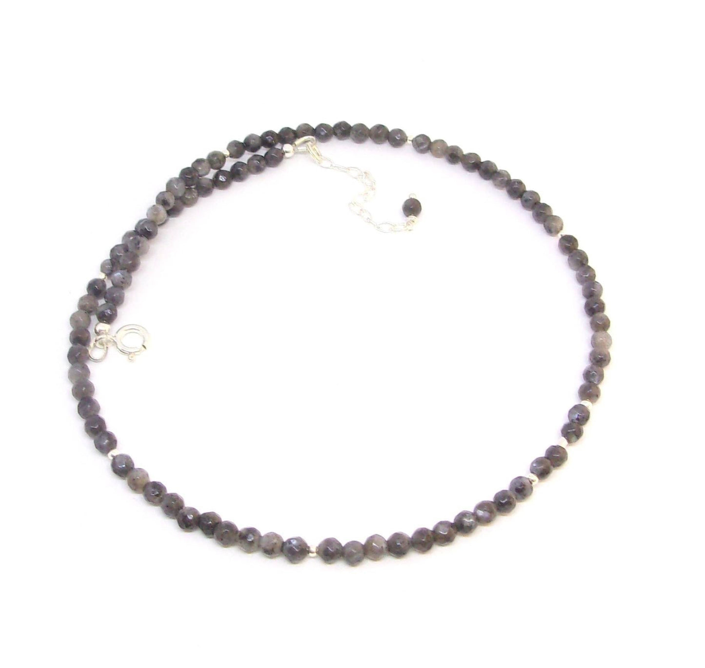 Collier  en argent 925, orné de pierres fines de labradorite noire, aussi appelée larvikite. Le collier mesure 40 cm de long, avec une chaîne supplémentaire pour ajustement. Les pierres de labradorite, de 4 mm de diamètre, apportent une touche élégante et mystérieuse.