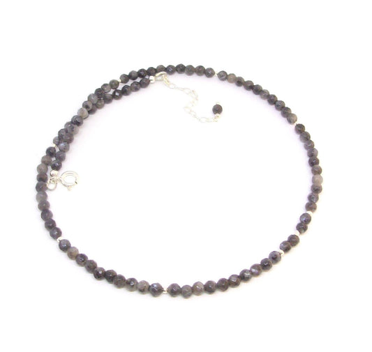 Collier  en argent 925, orné de pierres fines de labradorite noire, aussi appelée larvikite. Le collier mesure 40 cm de long, avec une chaîne supplémentaire pour ajustement. Les pierres de labradorite, de 4 mm de diamètre, apportent une touche élégante et mystérieuse.