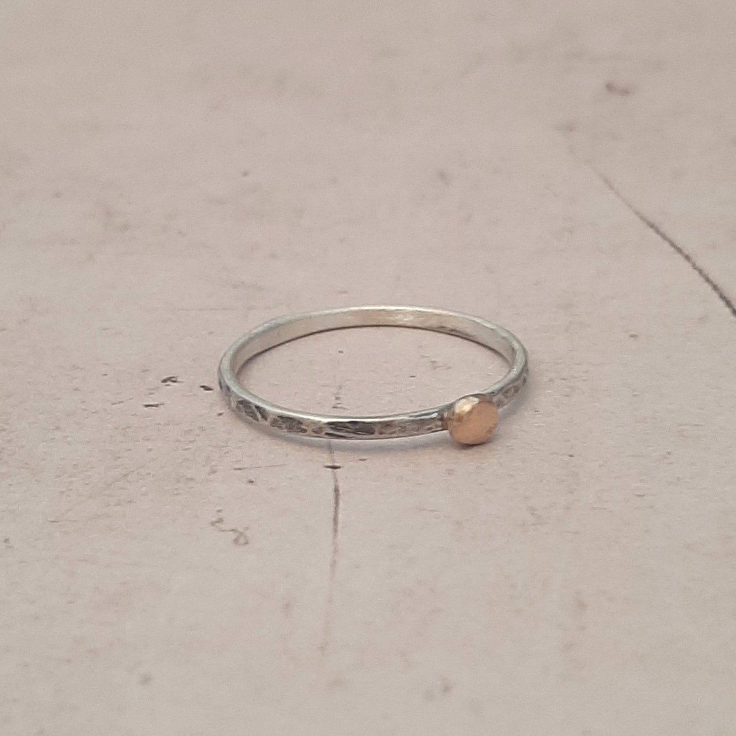 Bague fine ethnique en argent massif patiné, agrémentée d'une petite perle en or 9 carats. Son design élégant et artisanal combine l'authenticité de l'argent martelé avec l'éclat subtil de l’or, créant ainsi un bijou unique .