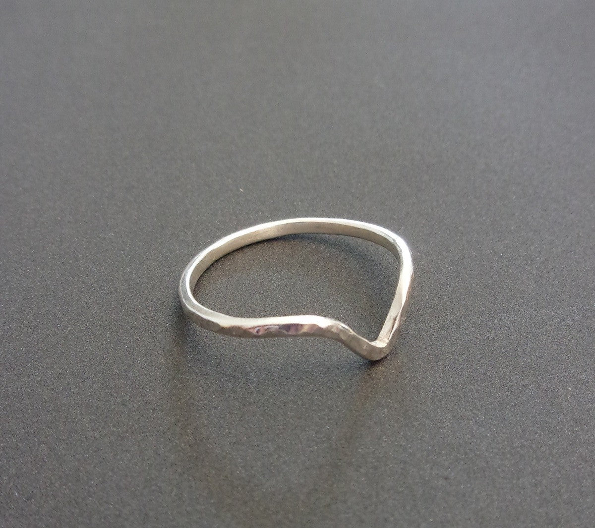 Bague Chevron en Argent Massif Martelé", un bijou minimaliste en argent massif, parfait pour une touche d'élégance. Elle peut être portée seule ou en superposition avec d'autres bagues. Faite à la main en France, chaque bague est fabriquée sur commande avec un délai de livraison de 3 jours. Le design simple et épuré de 1,5 mm de largeur convient à diverses tailles de doigts. Cette bague se distingue par son côté artisanal et sa fabrication responsable.