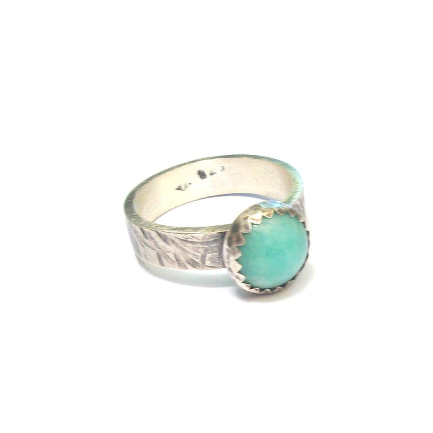 Découvrez la bague ethnique en argent massif, ornée d'une pierre d'amazonite du Pérou. Avec une largeur d'anneau de 4 mm et un cabochon de 8 mm, ce bijou unique, fait main en France, symbolise l'élégance et la spiritualité. L'amazonite, pierre apaisante, stimule la joie de vivre, la communication et l'inspiration. Chaque pièce étant artisanale, de légères variations peuvent survenir.