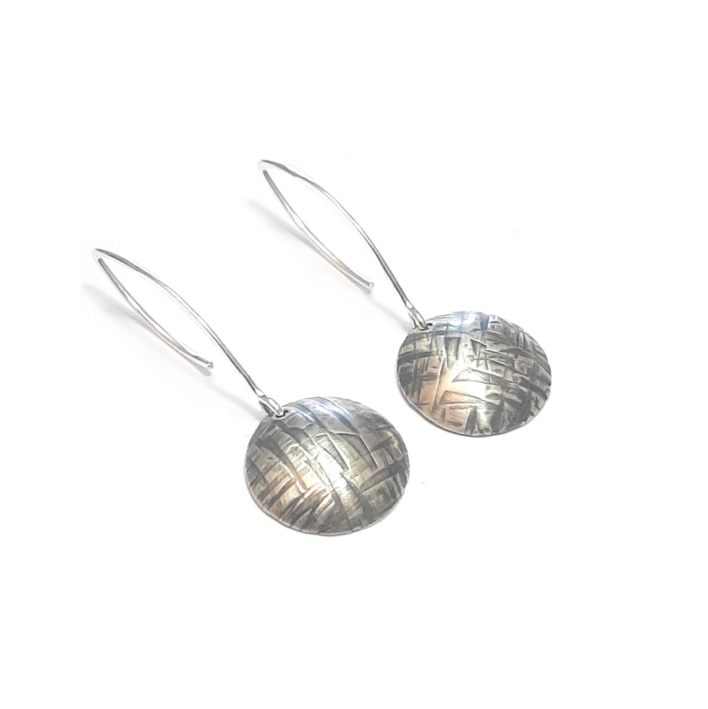 Boucles d'oreilles rondes en argent massif martelé et patiné, inspirées par la texture du tronc du "tucum", un palmier tropical. Chaque bijou est façonné à la main, rendant chaque pièce unique. De petites différences peuvent apparaître par rapport au modèle photographié. La longueur est d'environ 4.6 cm.