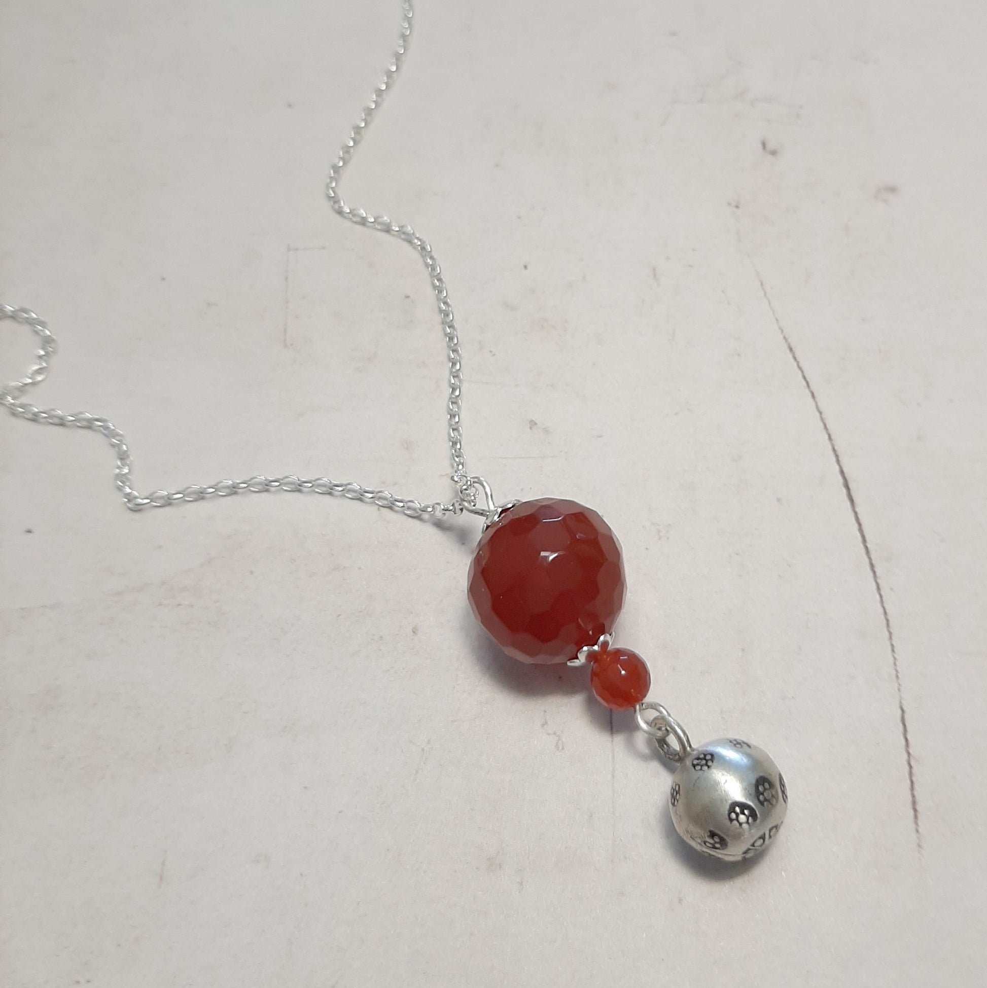 Pendentif bola cornaline 18 mm et petite cloche argent 925 fait main.
bijou sonore