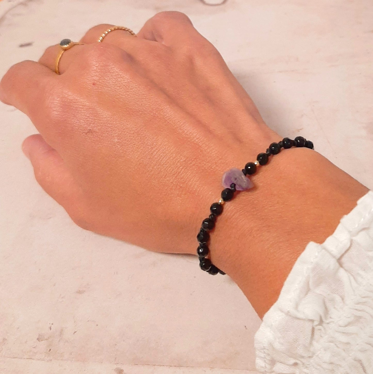 Bracelet brésilien en pierres naturelles d'onyx, orné d'une améthyste brute en son centre. Un bracelet porte-bonheur, ajustable grâce à sa fermeture coulissante.