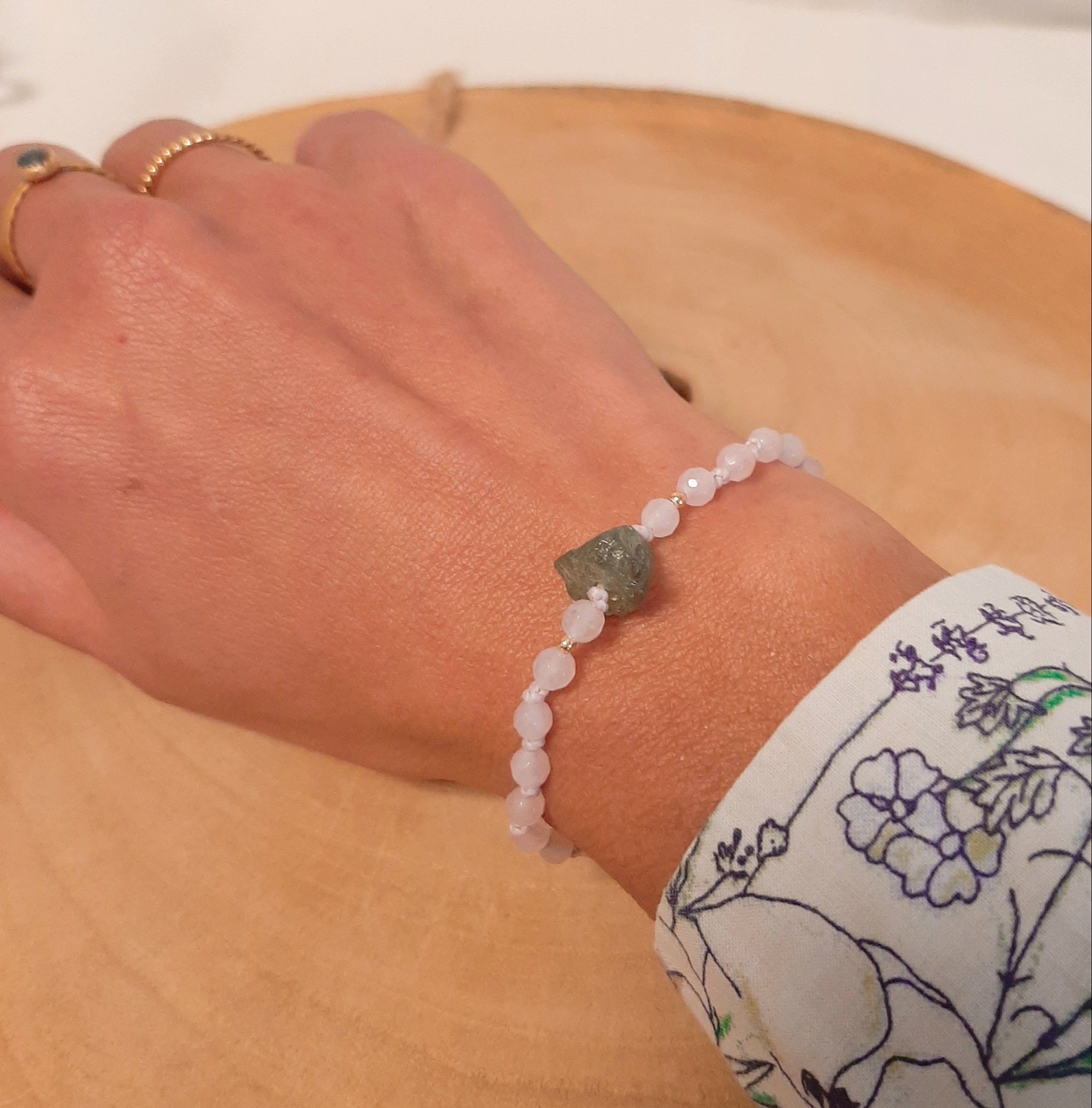Bracelet brésilien en pierres naturelles de quartz rose, orné d'ungrenat vert  brut en son centre. Un bracelet porte-bonheur, ajustable grâce à sa fermeture coulissante.