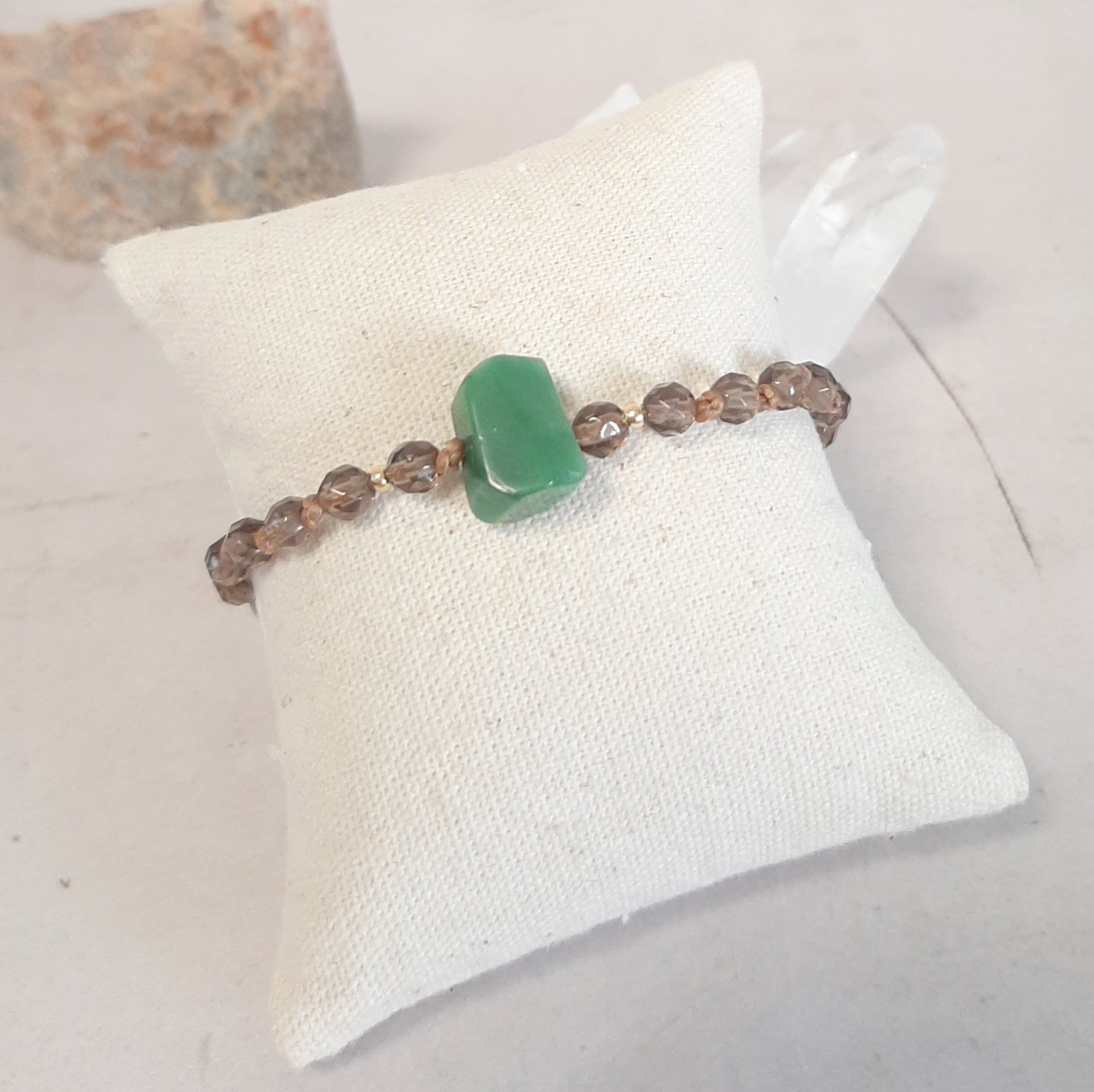 Bracelet ajustable en Quartz fumé et Jade – Apaisement & Ancrage
Ce bracelet en pierres naturelles associe le quartz fumé, reconnu pour ses vertus d’ancrage et d’apaisement, à une jade brute centrale, symbole de sagesse et d’équilibre. Noué à la main, il est sublimé par des apprêts en argent 925 doré.

Son cordon coulissant permet un ajustement parfait à tous les poignets. 