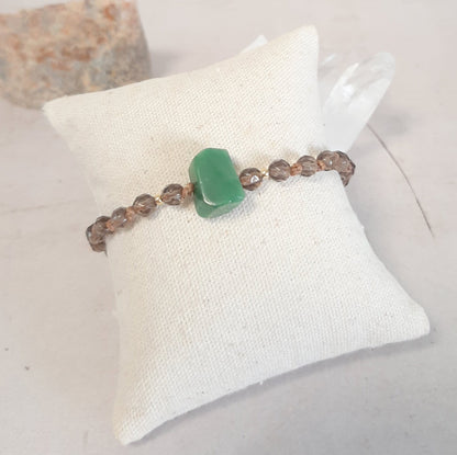 Bracelet ajustable en Quartz fumé et Jade – Apaisement & Ancrage
Ce bracelet en pierres naturelles associe le quartz fumé, reconnu pour ses vertus d’ancrage et d’apaisement, à une jade brute centrale, symbole de sagesse et d’équilibre. Noué à la main, il est sublimé par des apprêts en argent 925 doré.

Son cordon coulissant permet un ajustement parfait à tous les poignets. 