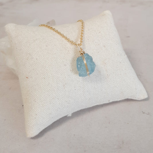 Vue rapprochée du pendentif aigue-marine brute sur chaîne dorée. Collier en cristal brut 