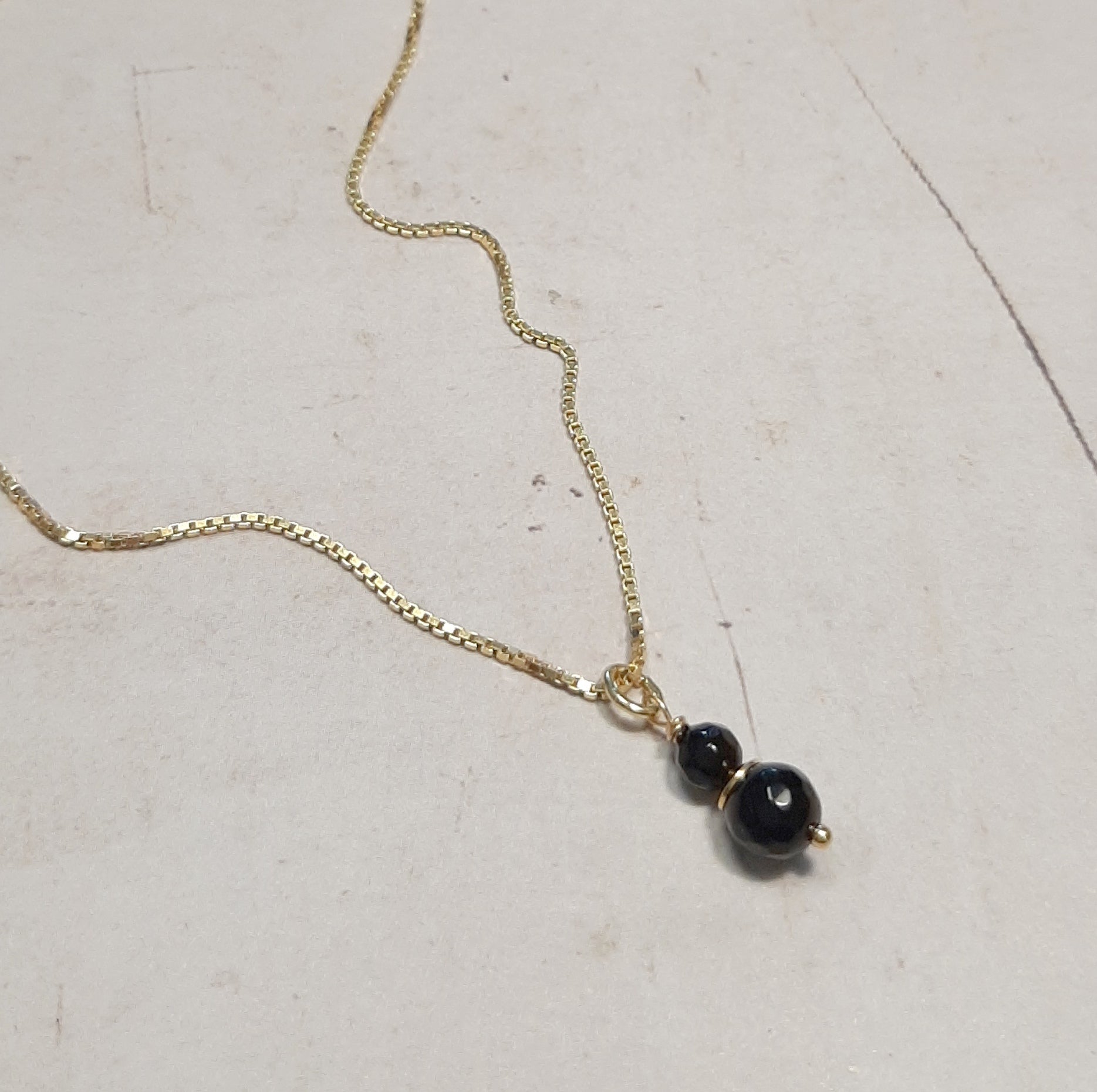 Zoom sur la chaîne fine du Collier Talisman Onyx et le fermoir, mettant en évidence la qualité de l'argent 925 doré.