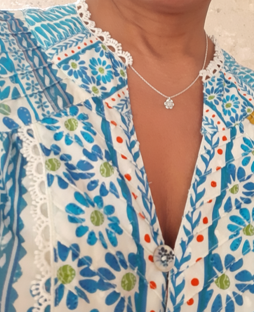 Présentation d'un collier appeleur d'anges, porté sur une femme en chemisier à motifs.