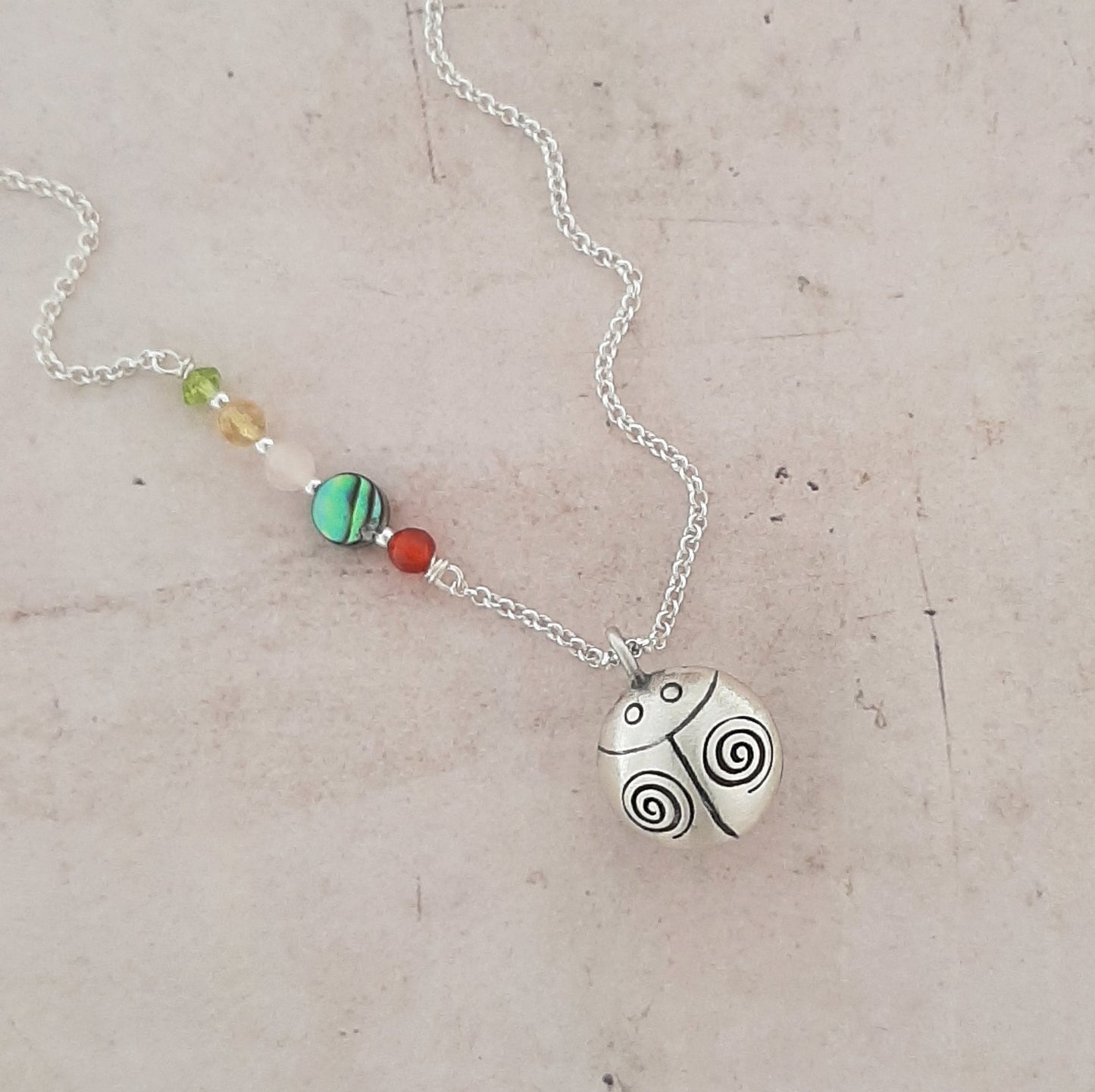collier en argent avec un appeleur d’anges en forme de coccinelle, symbole de chance, de protection et de douceur.