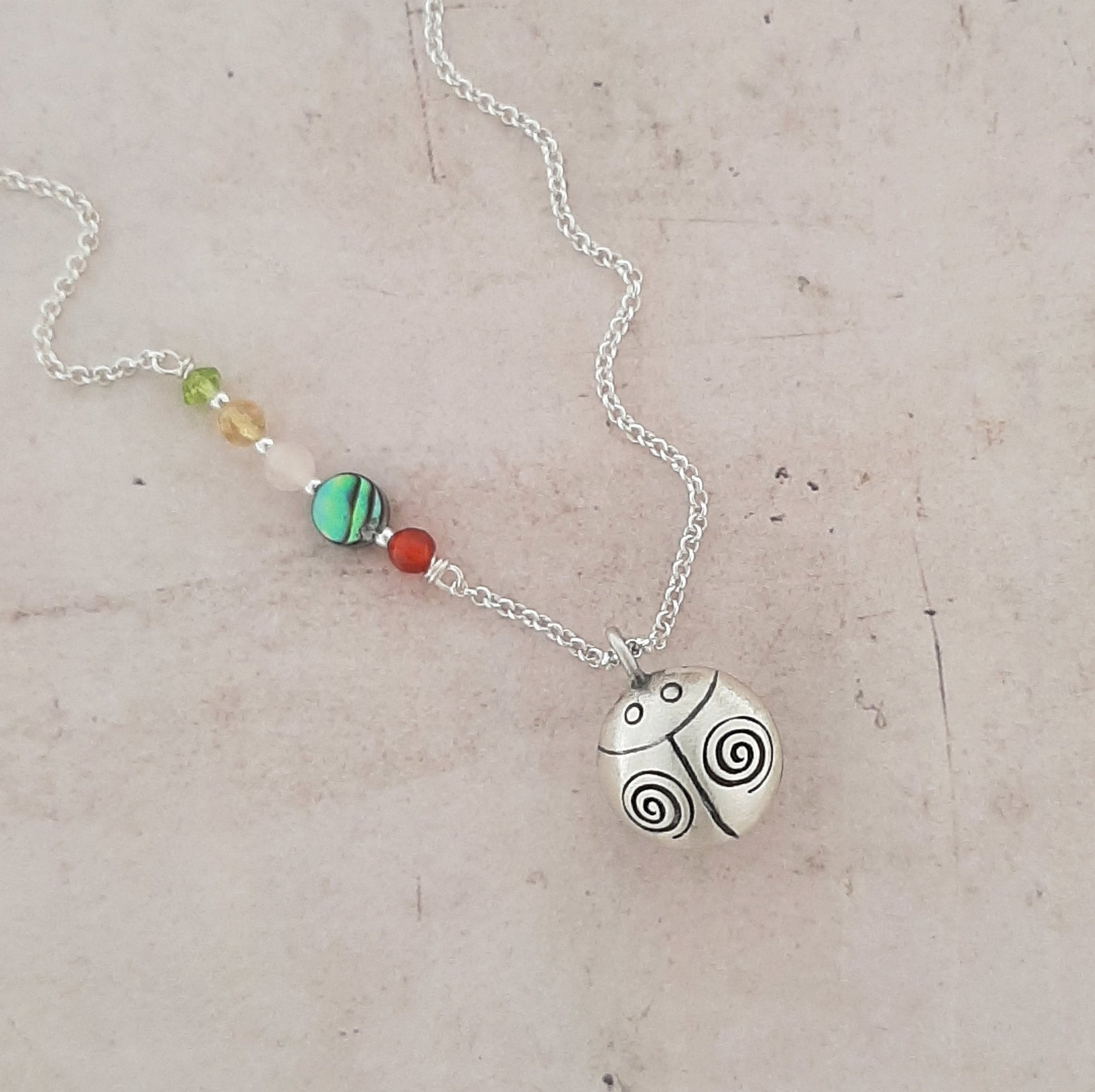 collier en argent avec un appeleur d’anges en forme de coccinelle, symbole de chance, de protection et de douceur.