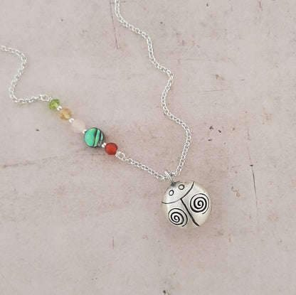 collier en argent avec un appeleur d’anges en forme de coccinelle, symbole de chance, de protection et de douceur.