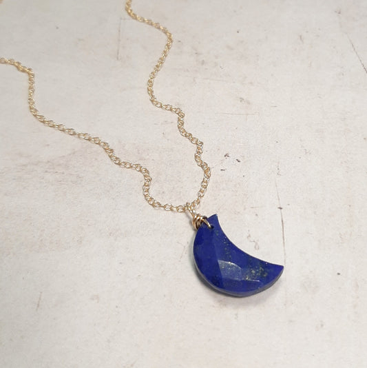 Découvrez ce collier en argent sterling doré, sublimé par un pendentif en forme de croissant de lune en lapis lazuli, une pierre précieuse aux nuances profondes. Ce bijou symbolise les cycles de la vie, l'intuition et la transformation spirituelle, rendant hommage à la féminité et à l'énergie lunaire. Longueur de 40 cm, ajustable grâce à une chaînette.