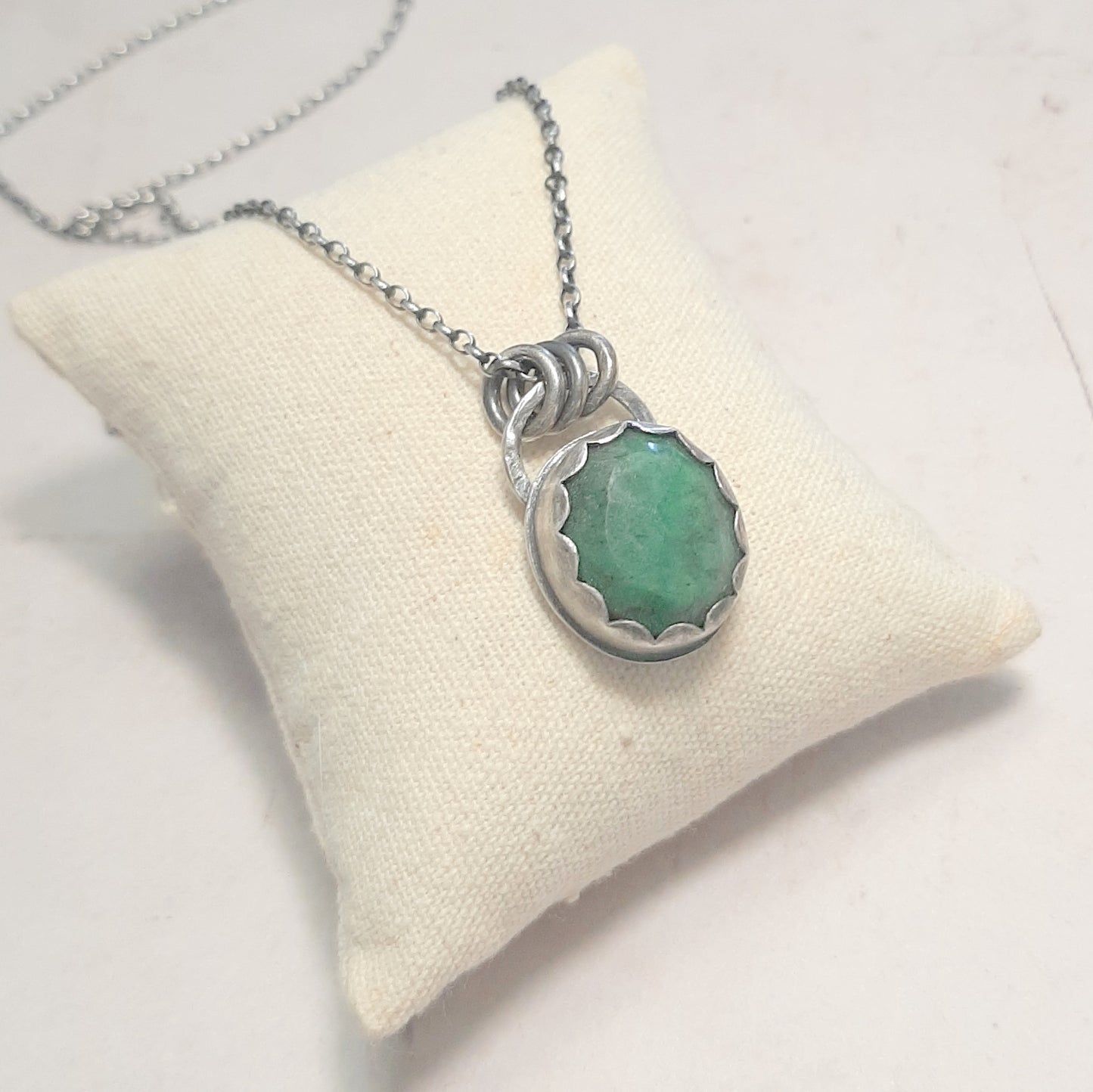 Pendentif émeraude naturelle serti en argent massif patiné, style vintage ethnique, sur coussin de présentation – bijou fait main