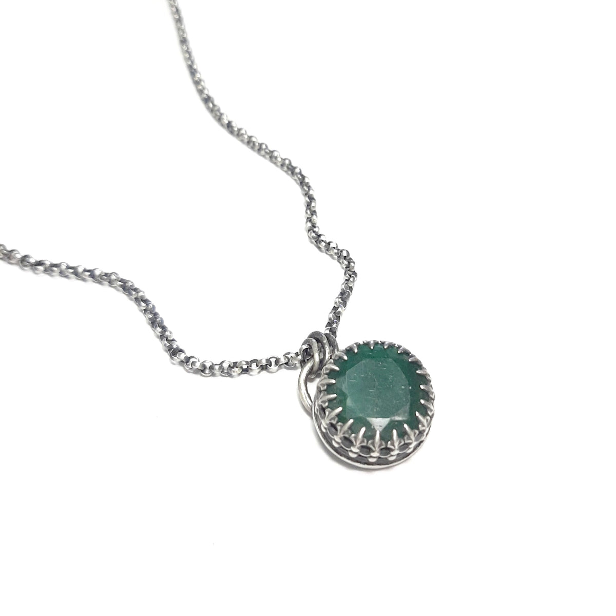 Collier ethnique à chaîne argentée et pendentif ovale en émeraude verte sur fond blanc.